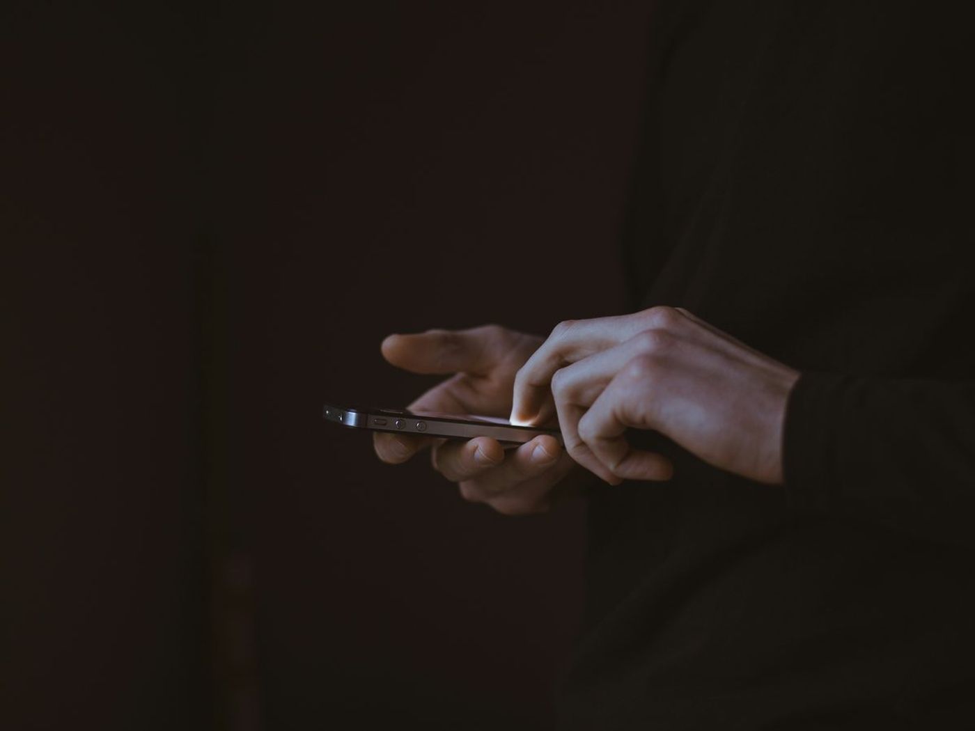 Hands holding a smartphone in a dark room