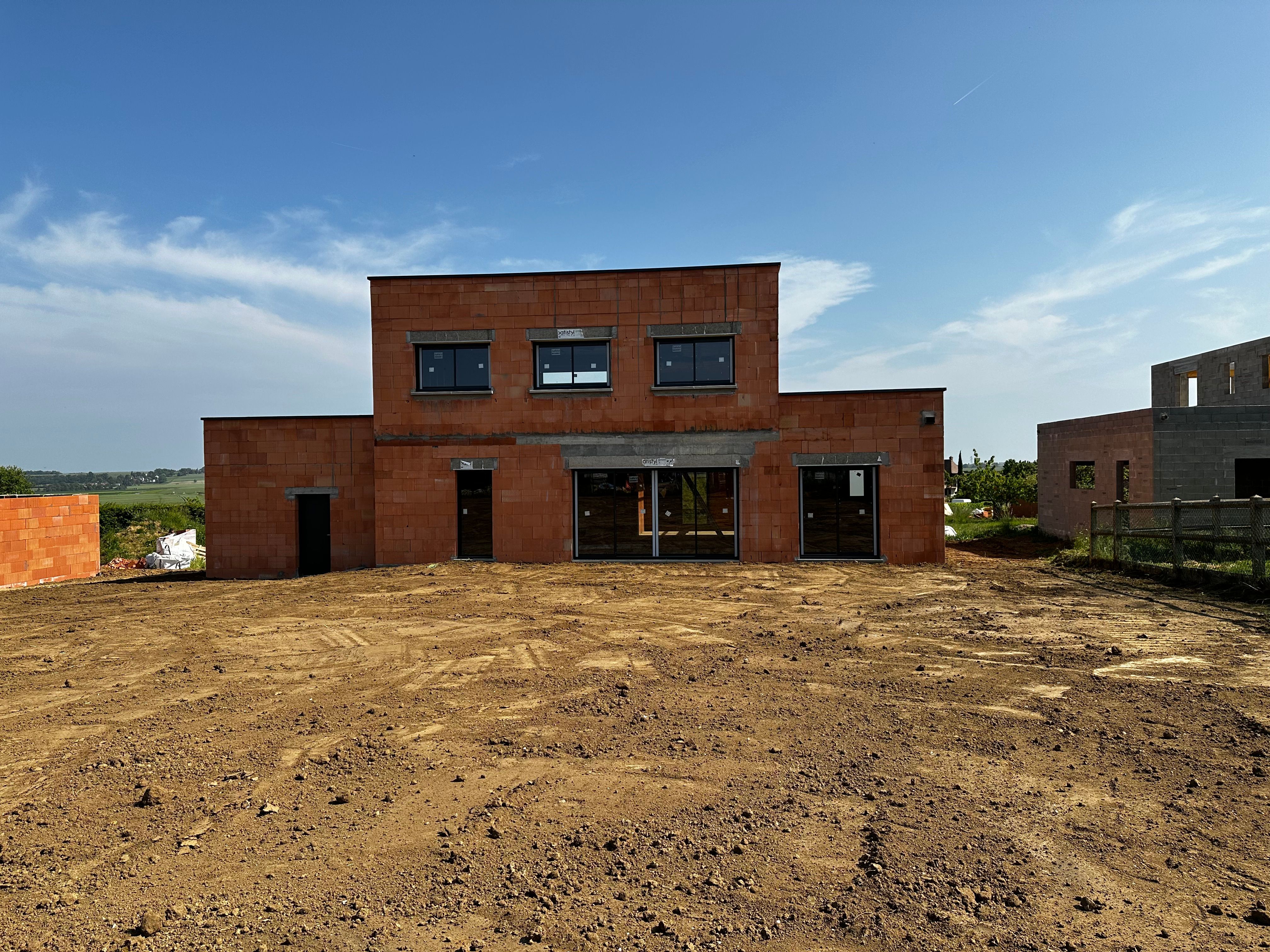 Maison en construction avec murs en parpaings et charpente en cours de pose