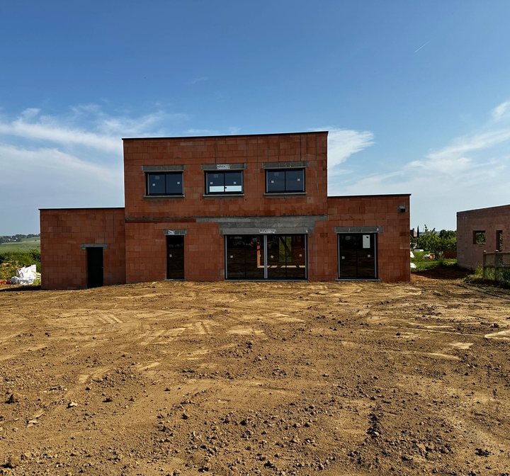Maison en construction avec murs en parpaings et charpente en cours de pose