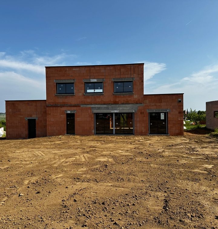 Maison en construction avec murs en parpaings et charpente en cours de pose
