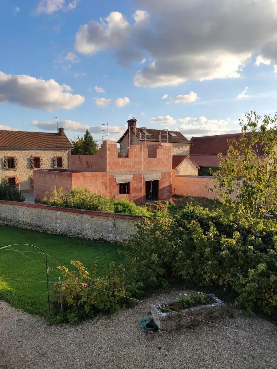 Construction neuve en briques vue de l’extérieur avec toiture en cours de finition