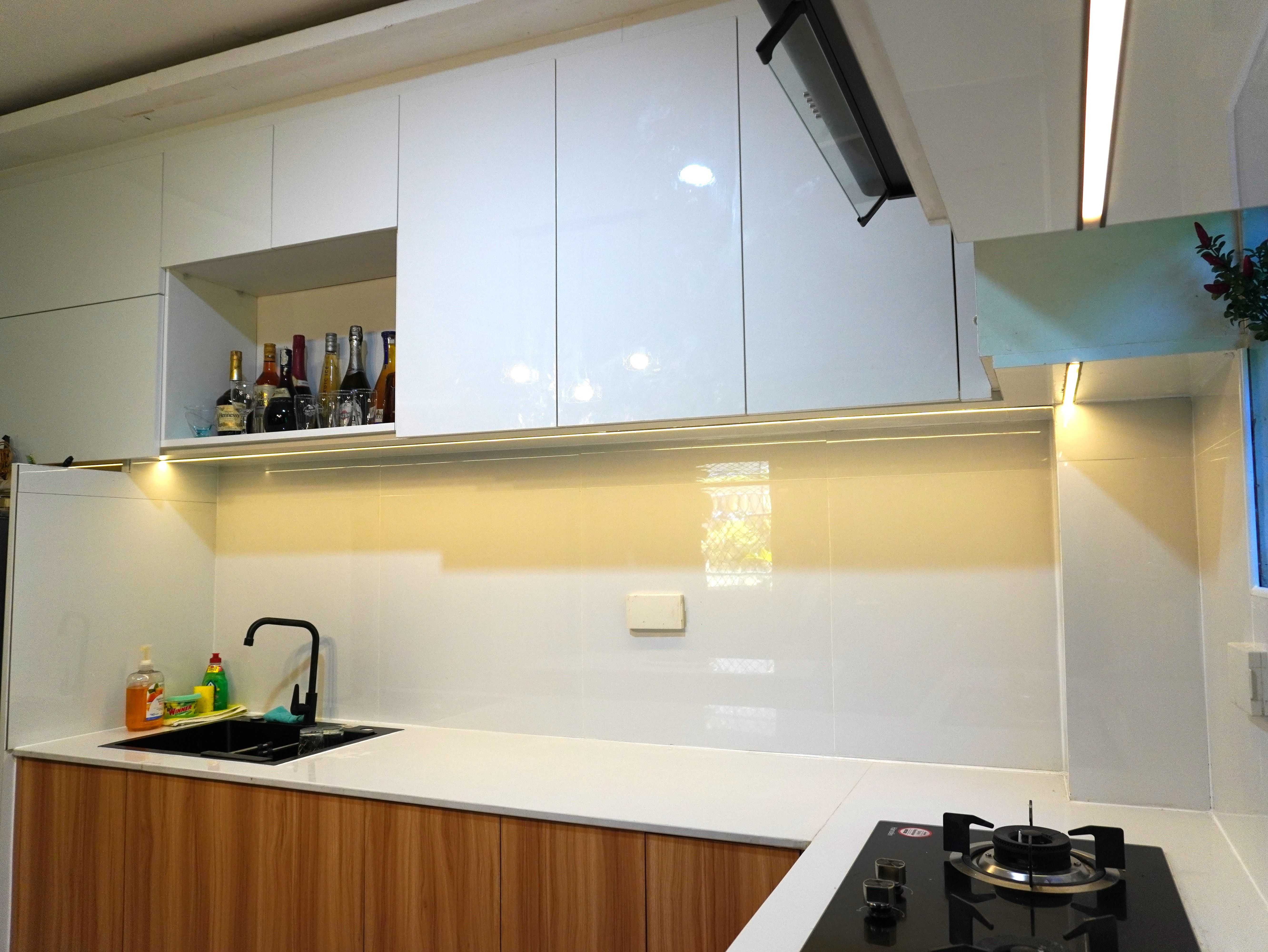 Custom-built kitchen cabinets with glossy white uppers, warm wood-grain base cabinets, and a fluted-panel island, designed for smart storage and a warm, modern look.