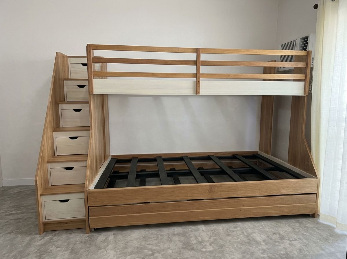 A natural wood bunk bed with a safety-railed top bunk, a wider bottom bed, a staircase with five storage drawers, and a pull-out trundle that sleeps a third. Space-saving and built to last.