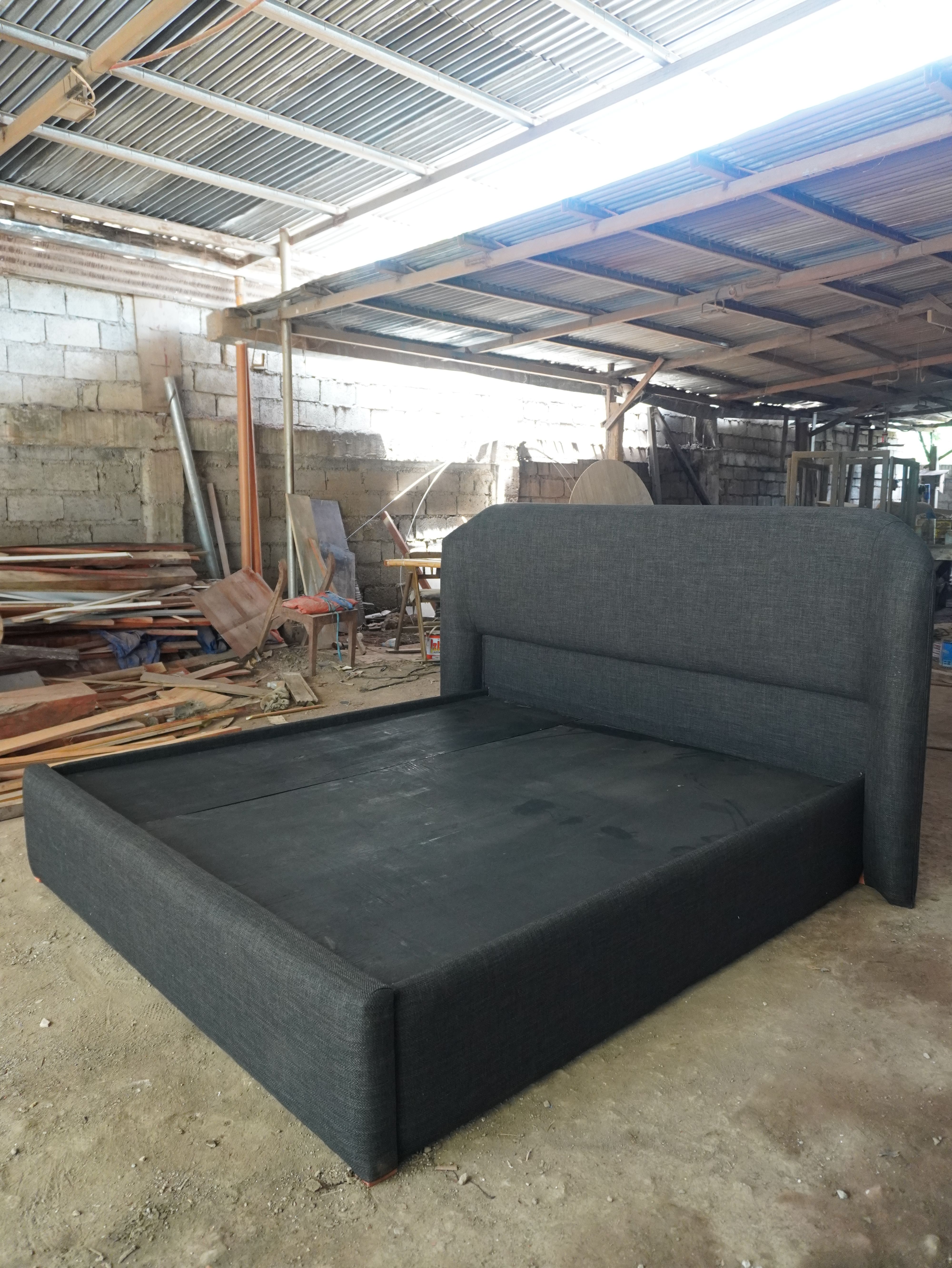 A king-sized upholstered bed in charcoal fabric with a tall, curved headboard, built for a clean, modern bedroom.
