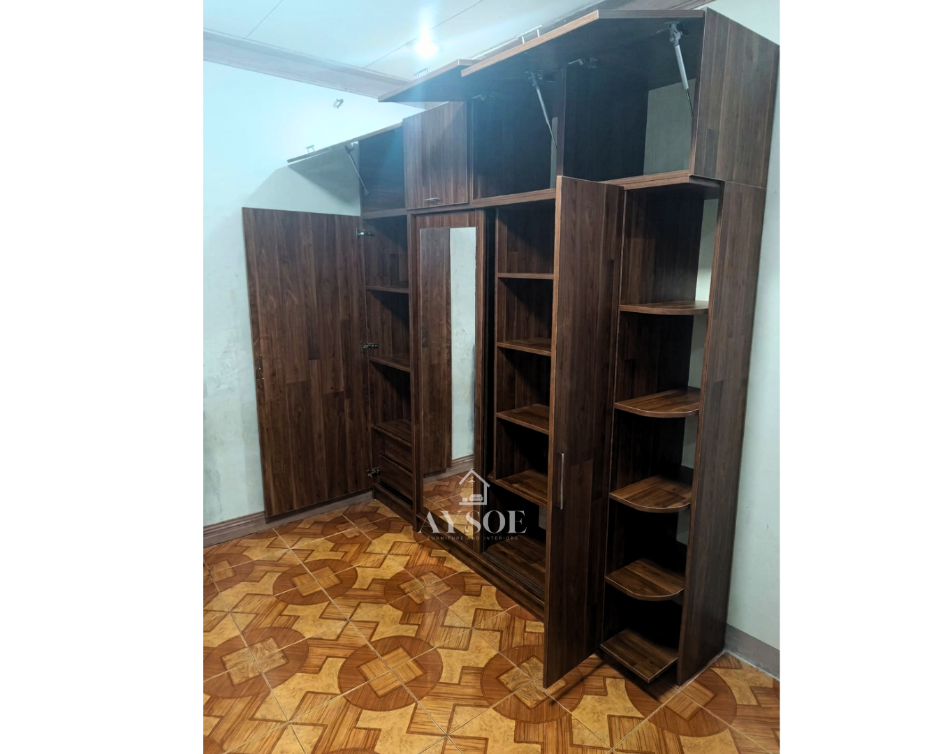 A large custom walnut-finish wardrobe with a mirror door, overhead cabinets, open shelves, and rounded corner shelves. Huge storage in one built-in unit.
