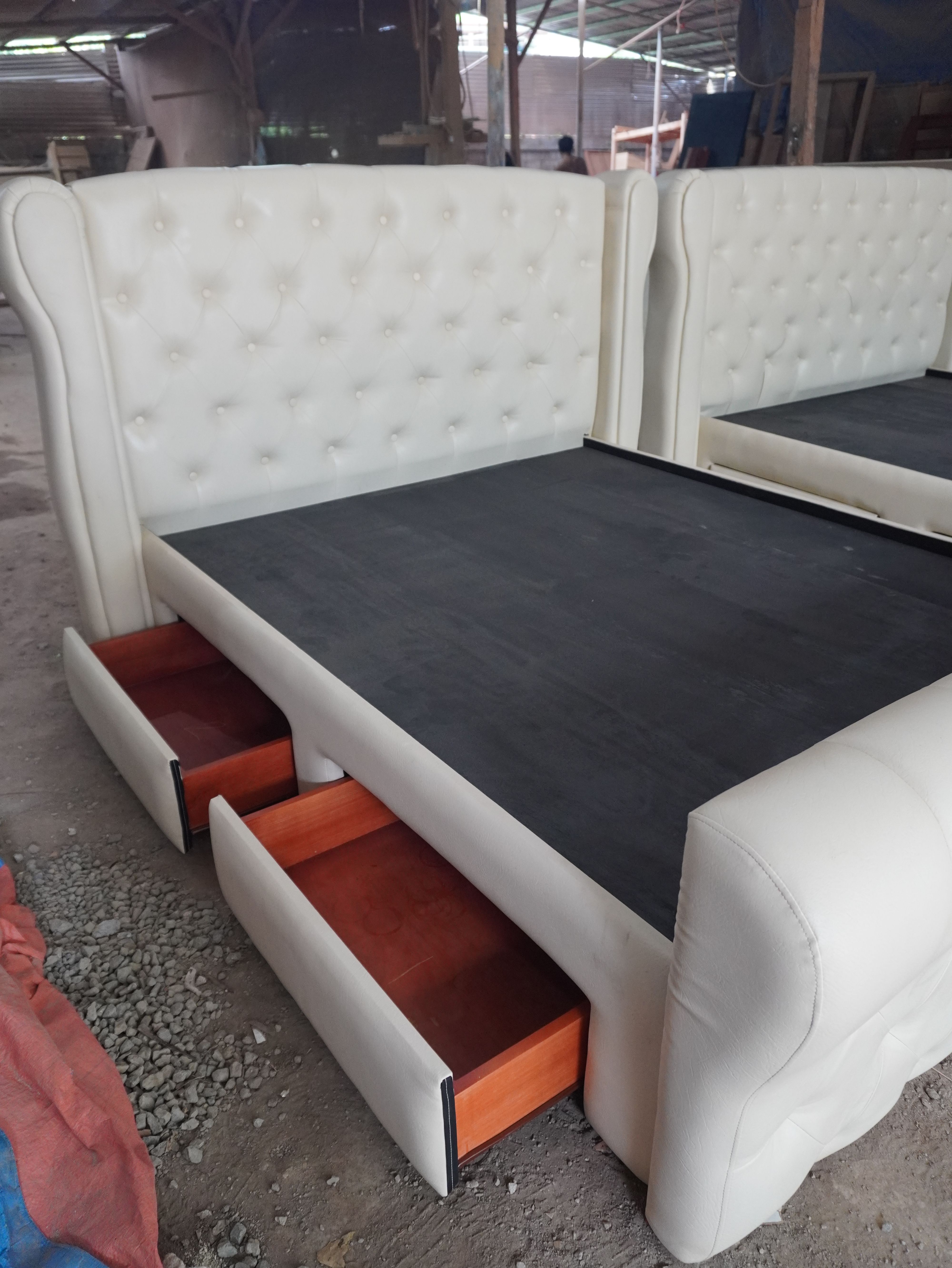 A classic cream leatherette bed with a tall button-tufted wingback headboard, a rolled sleigh footboard, and four built-in side drawers. Elegant, easy to wipe clean, and made to hold a lot.