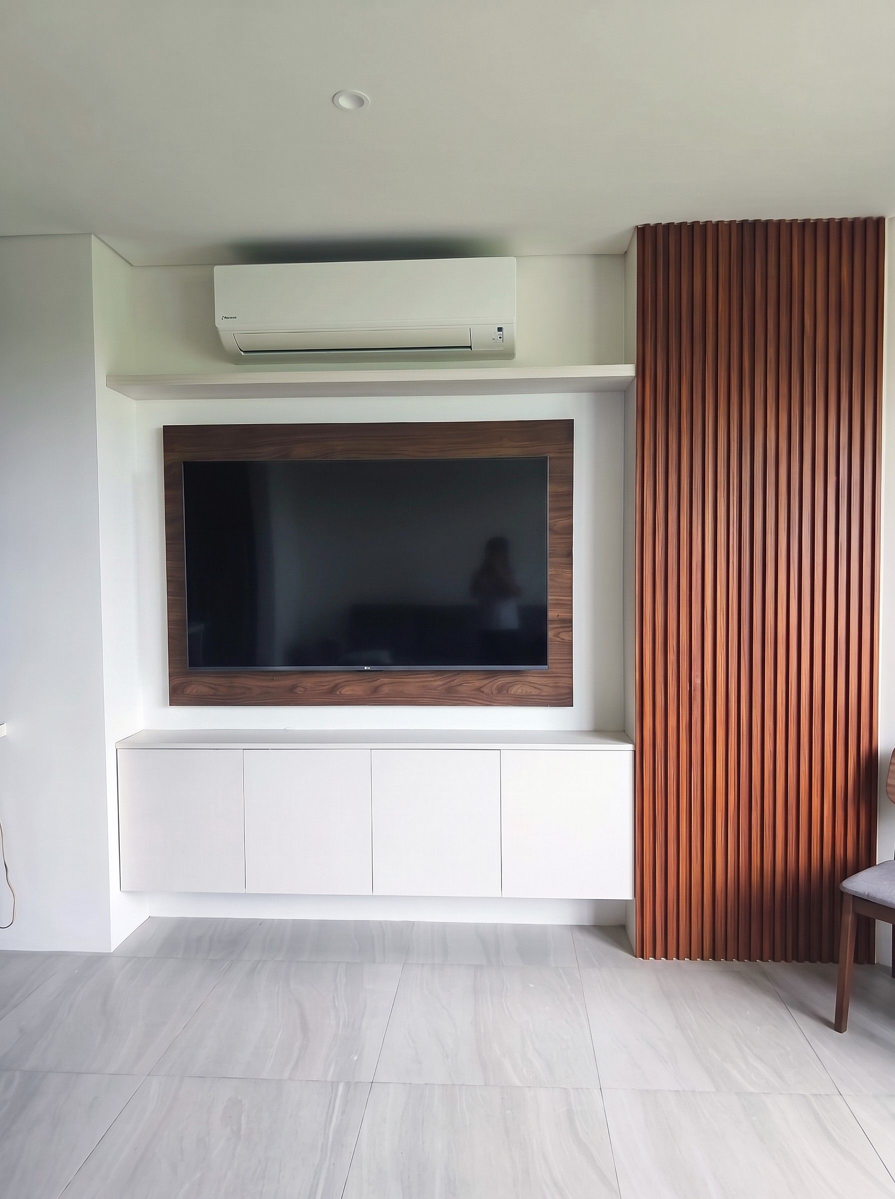 Custom floating TV unit with sleek white cabinetry, wood-finish TV panel, and vertical slat accent wall.