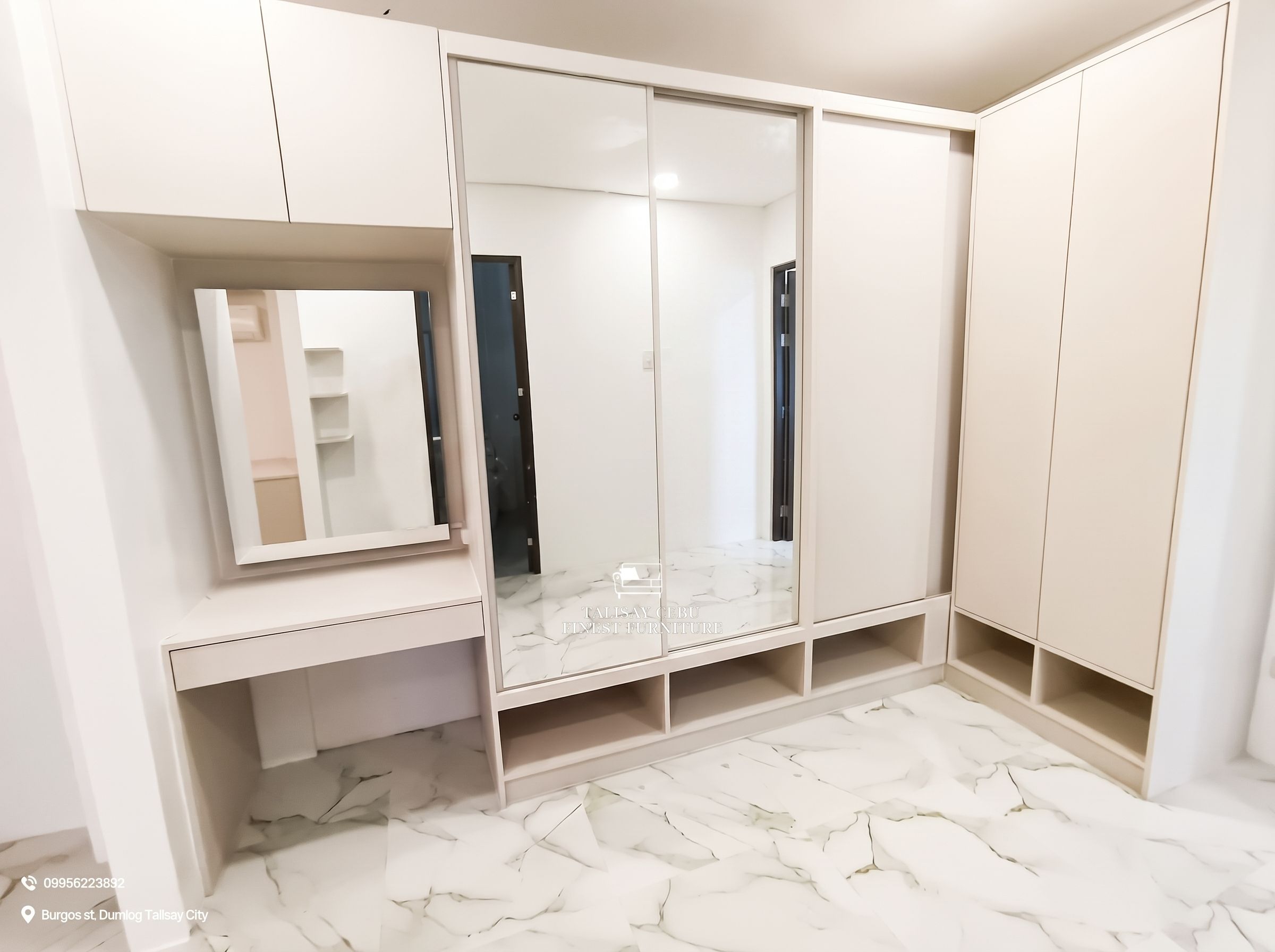 a custom floor-to-ceiling cream wardrobe with sliding mirror doors, open shoe cubbies, and a built-in vanity with drawer and overhead storage.