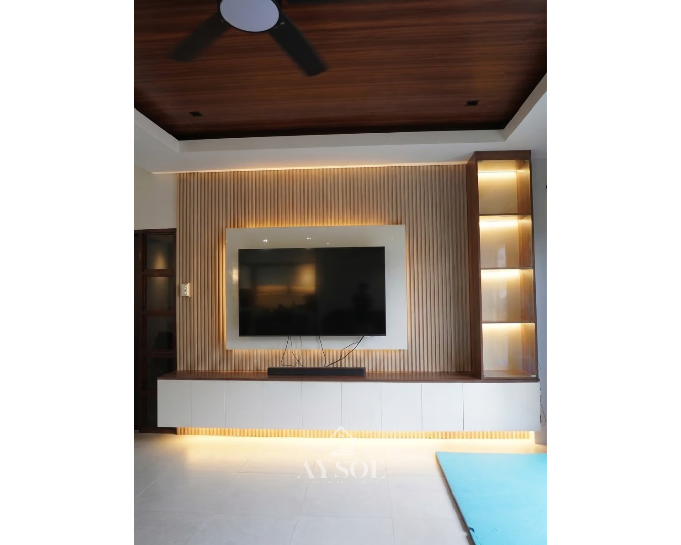 A built-in TV wall with a wood-slat feature panel, floating white cabinet, and a lit glass-door display tower. Made to fit your wall.