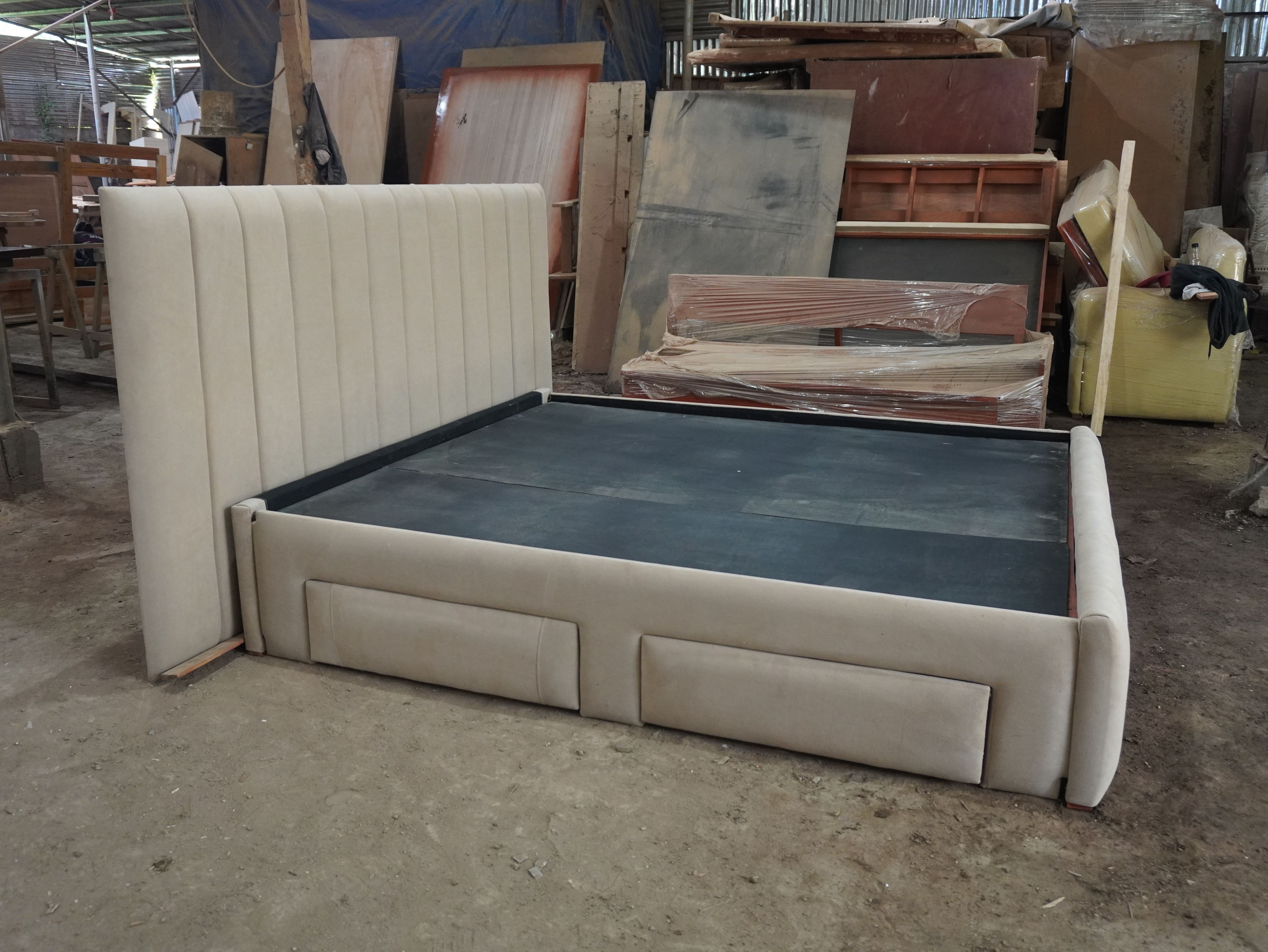 A calm, modern storage bed in soft sand-beige fabric, with an oversized vertical channel headboard, a matching channel footboard, and four upholstered side drawers that blend into the frame.