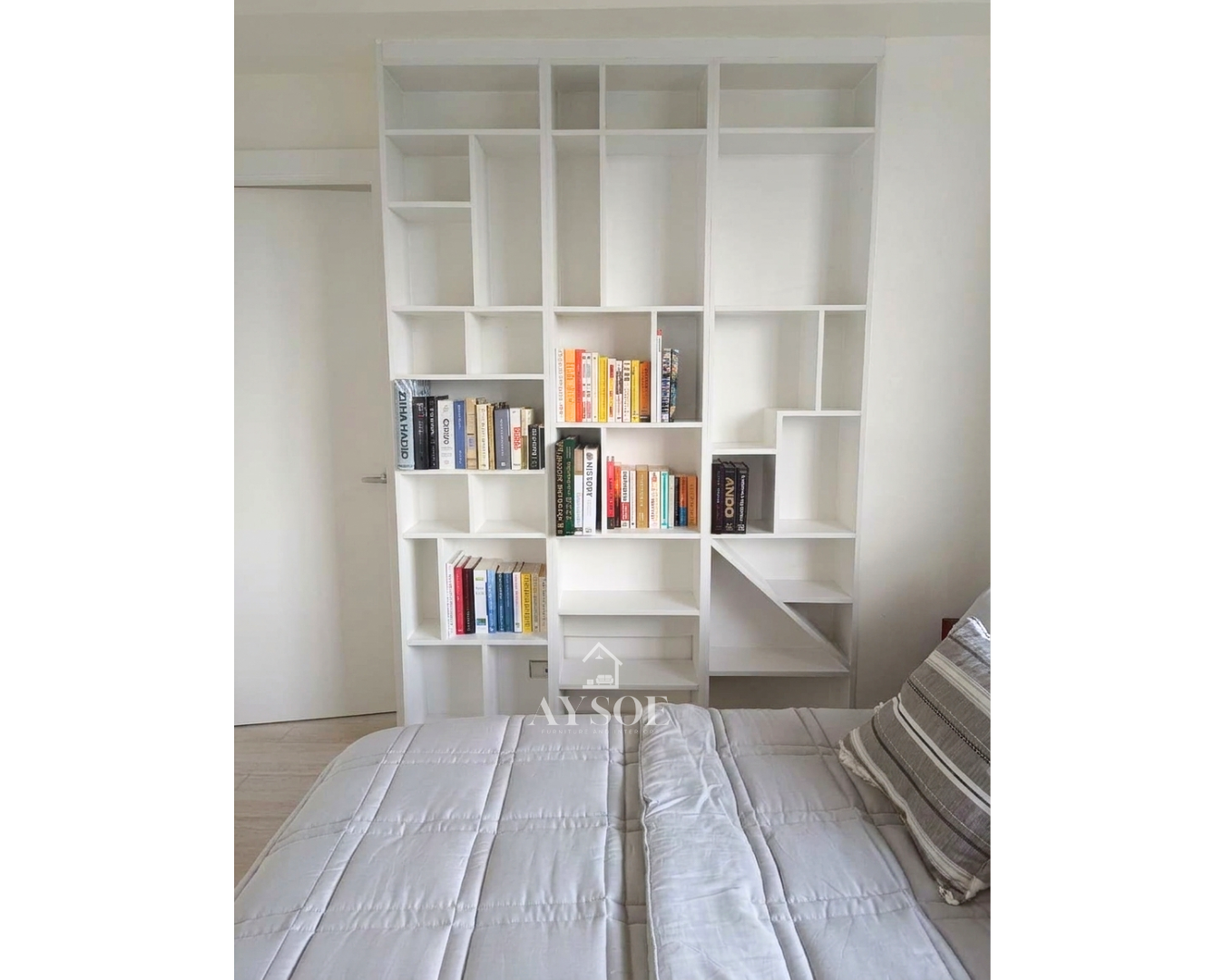 A floor-to-ceiling white bookshelf with geometric open cubbies in mixed sizes. Modern storage and display for books, decor, and collectibles.