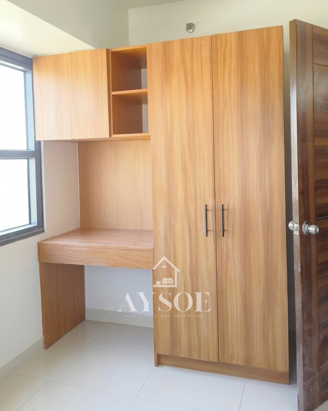 A custom honey oak wardrobe with a hanging rod, shelf, and pull-out drawer, plus a built-in study desk with overhead cabinets. Complete storage and a work spot for small rooms.