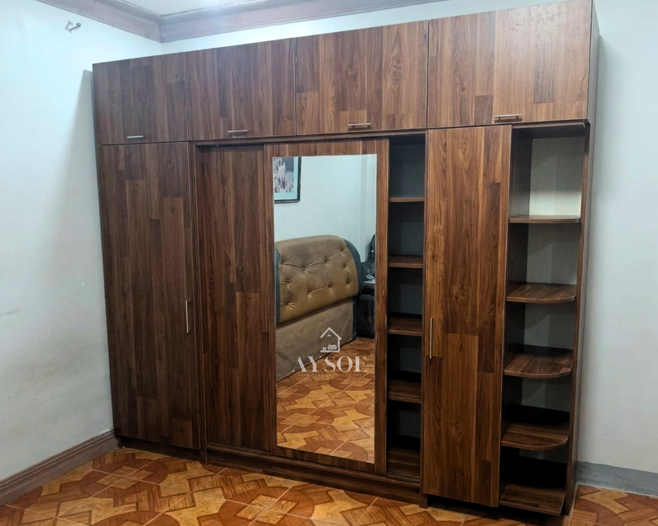 A large custom walnut-finish wardrobe with a mirror door, overhead cabinets, open shelves, and rounded corner shelves. Huge storage in one built-in unit.