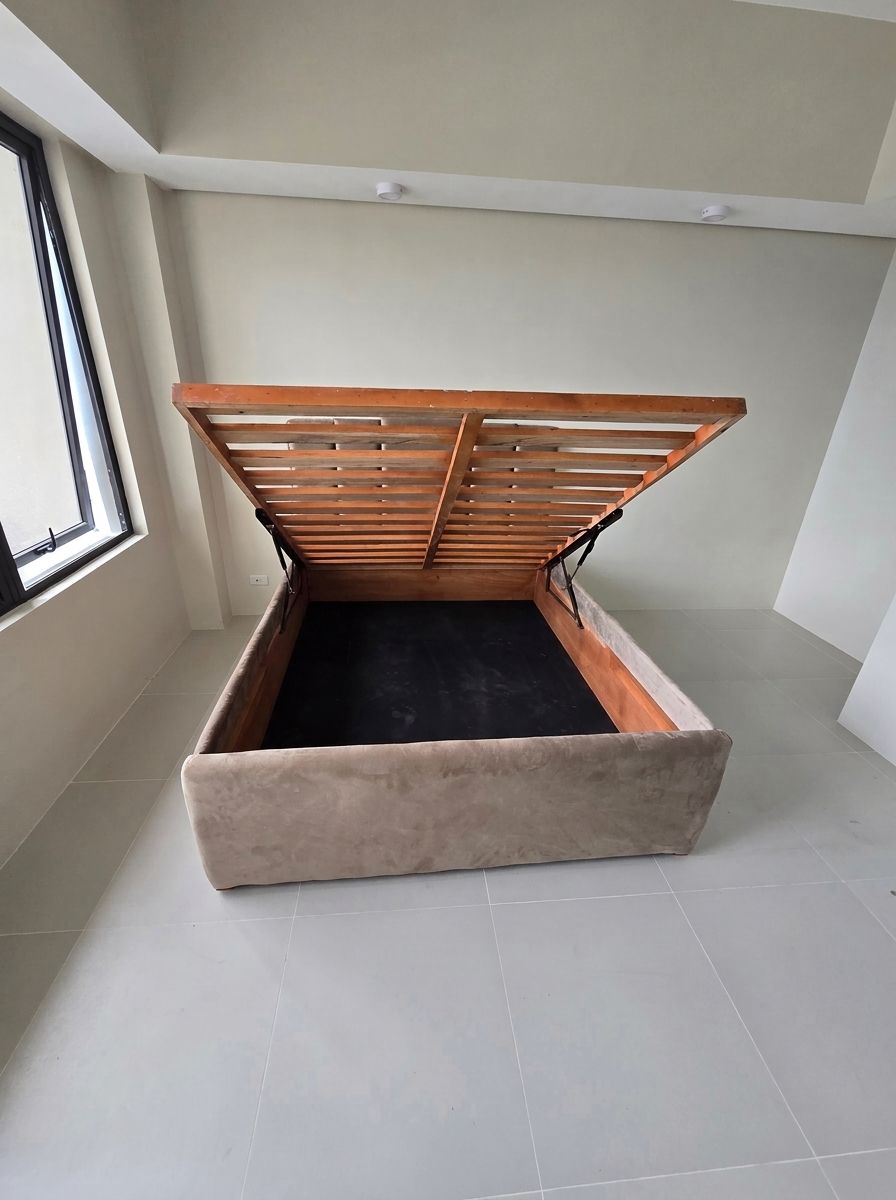 A modern upholstered bed in soft taupe suede-style fabric, with a vertical channel headboard and a gas-lift base that opens to a huge hidden storage space. Clean, calm, and built to save space in condos and bedrooms.