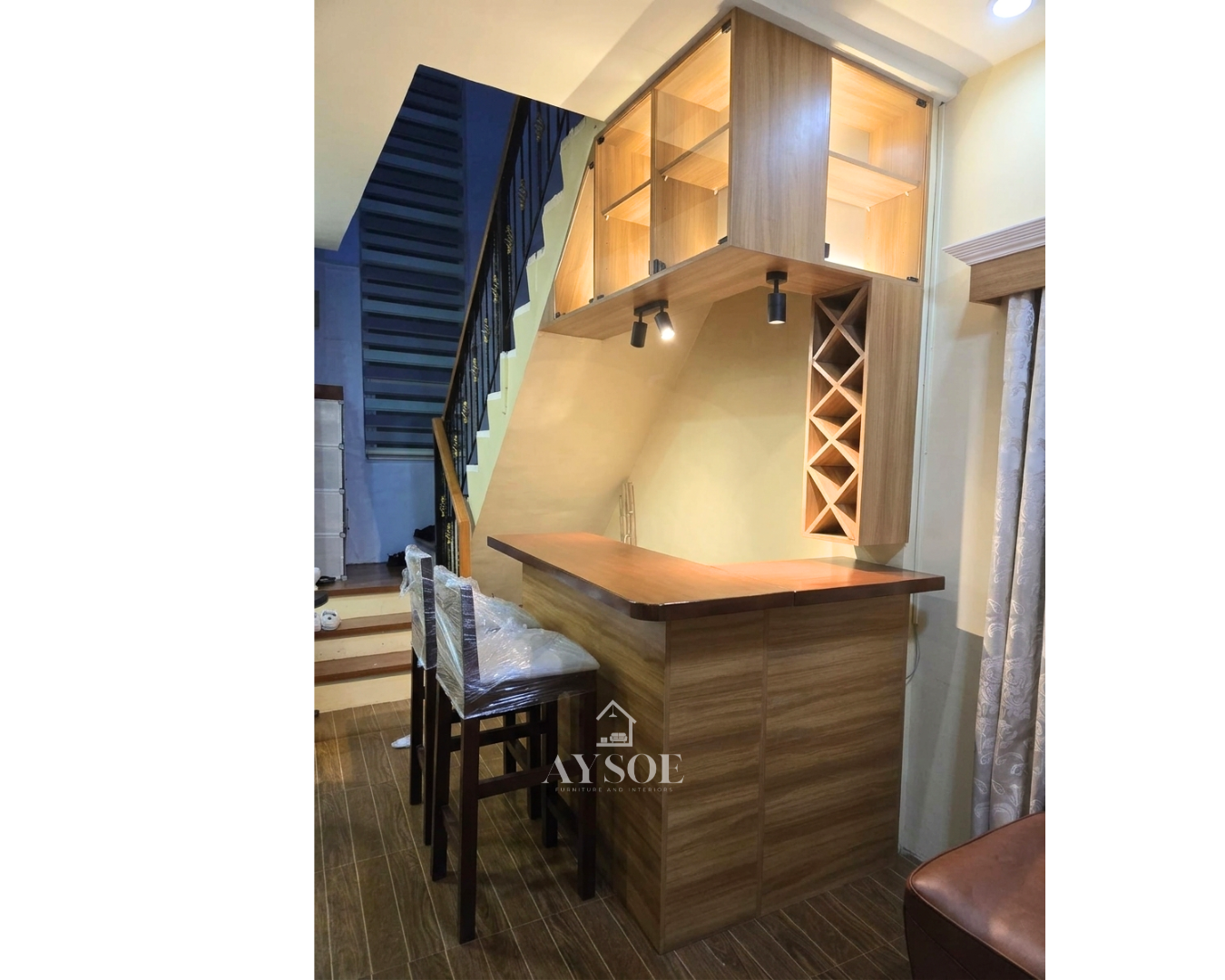 A custom home bar set with a wood-grain bar counter, lighted glass display cabinets, spotlights, and a diamond wine rack. Turns an unused corner into a stylish home bar.