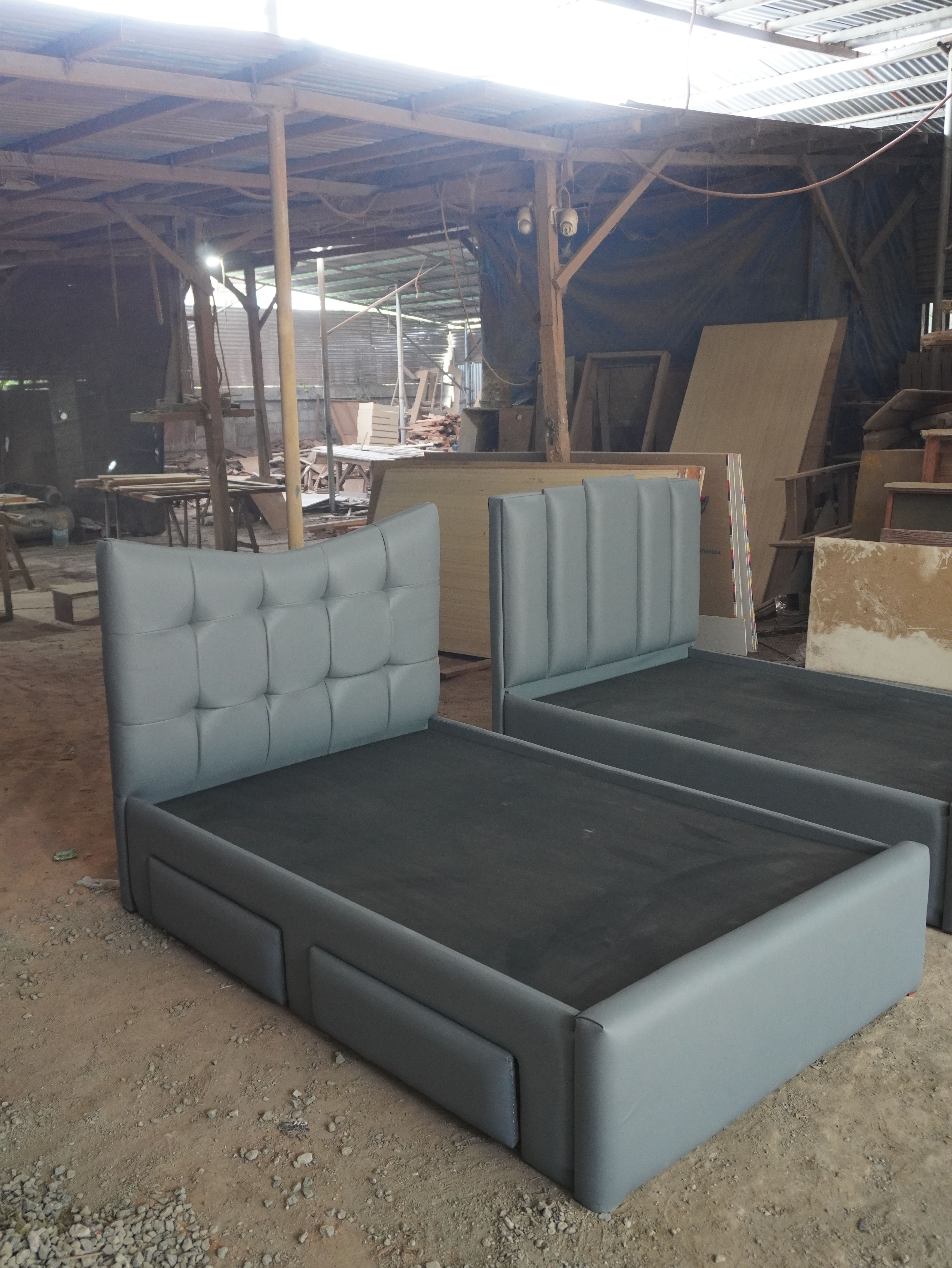 A modern upholstered bed in soft steel-blue leatherette, with a curved-top headboard of plush square tufted panels and a smooth, fully wrapped frame. Clean, distinctive, and easy to wipe clean.