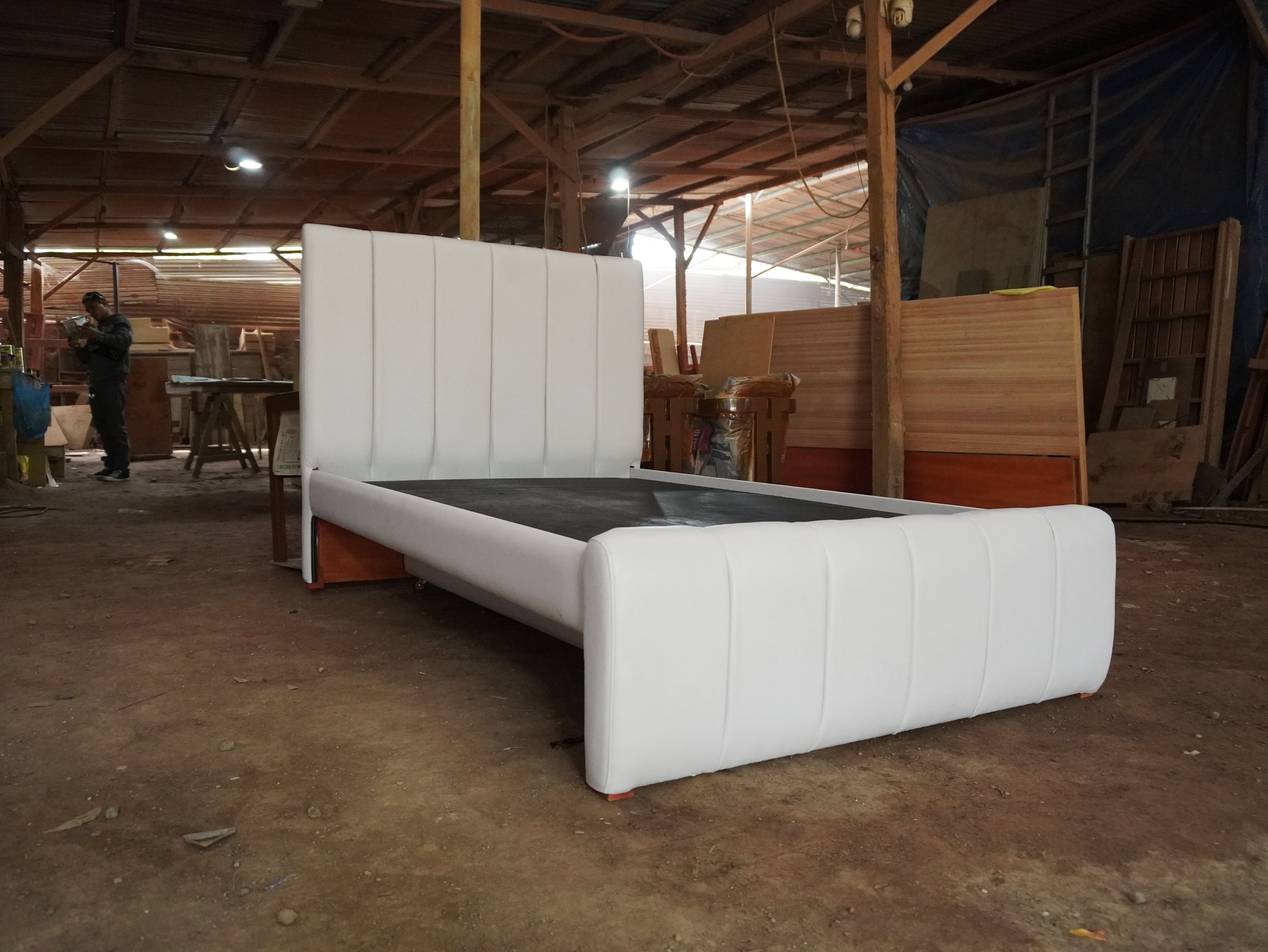 A clean white leatherette bed with a vertical channel headboard and footboard, plus a hidden pull-out bed on wheels. The pull-out can be set to slide out from either the left or right side to suit your room.