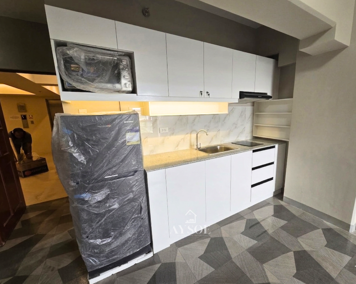 A compact straight kitchen set with glossy white cabinets, a built-in microwave niche, three drawers, and a granite-look countertop. Clean, bright, and made for condos and studios.