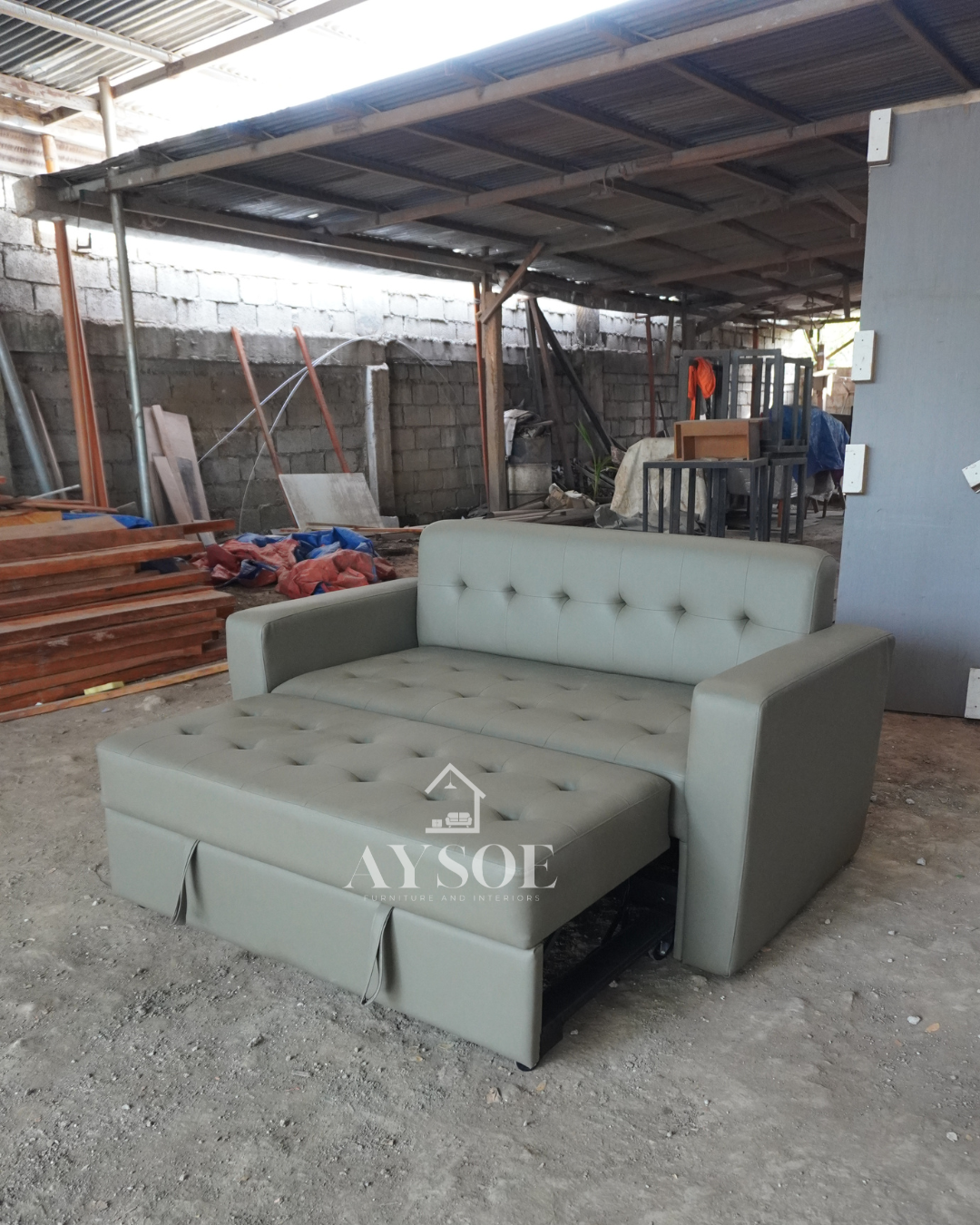 A 2-seater sofa that pulls out into a bed, in sage grey-green leatherette with a button-tufted back and seat. Two pieces of furniture in one, great for small spaces and guests.