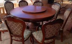 Chairs: Eight matching upholstered dining chairs featuring intricately carved, wavy wooden borders along the top of the backrests.