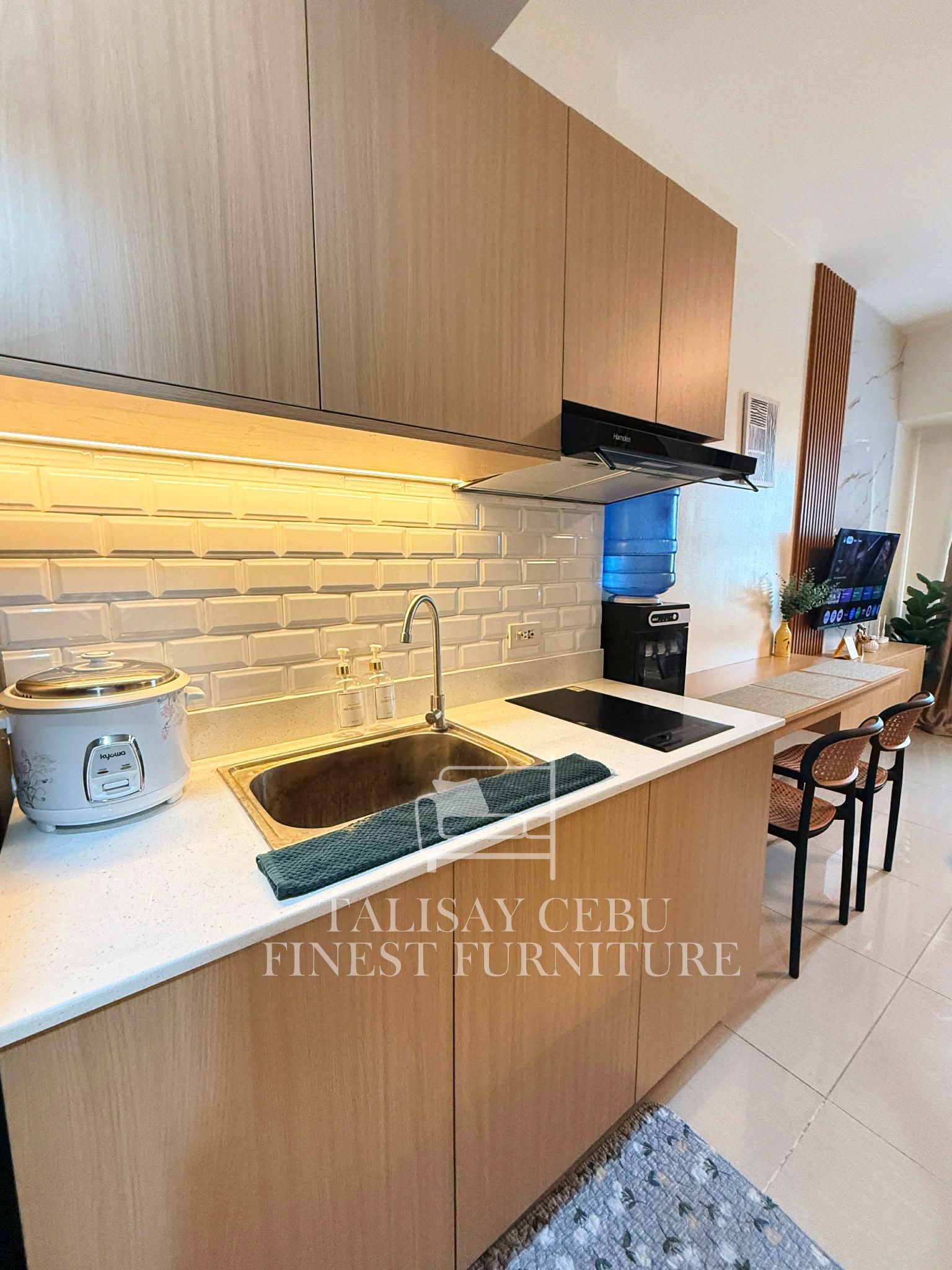 A compact kitchen with wood-grain cabinets, quartz counters, subway-tile backsplash, and under-cabinet lighting.