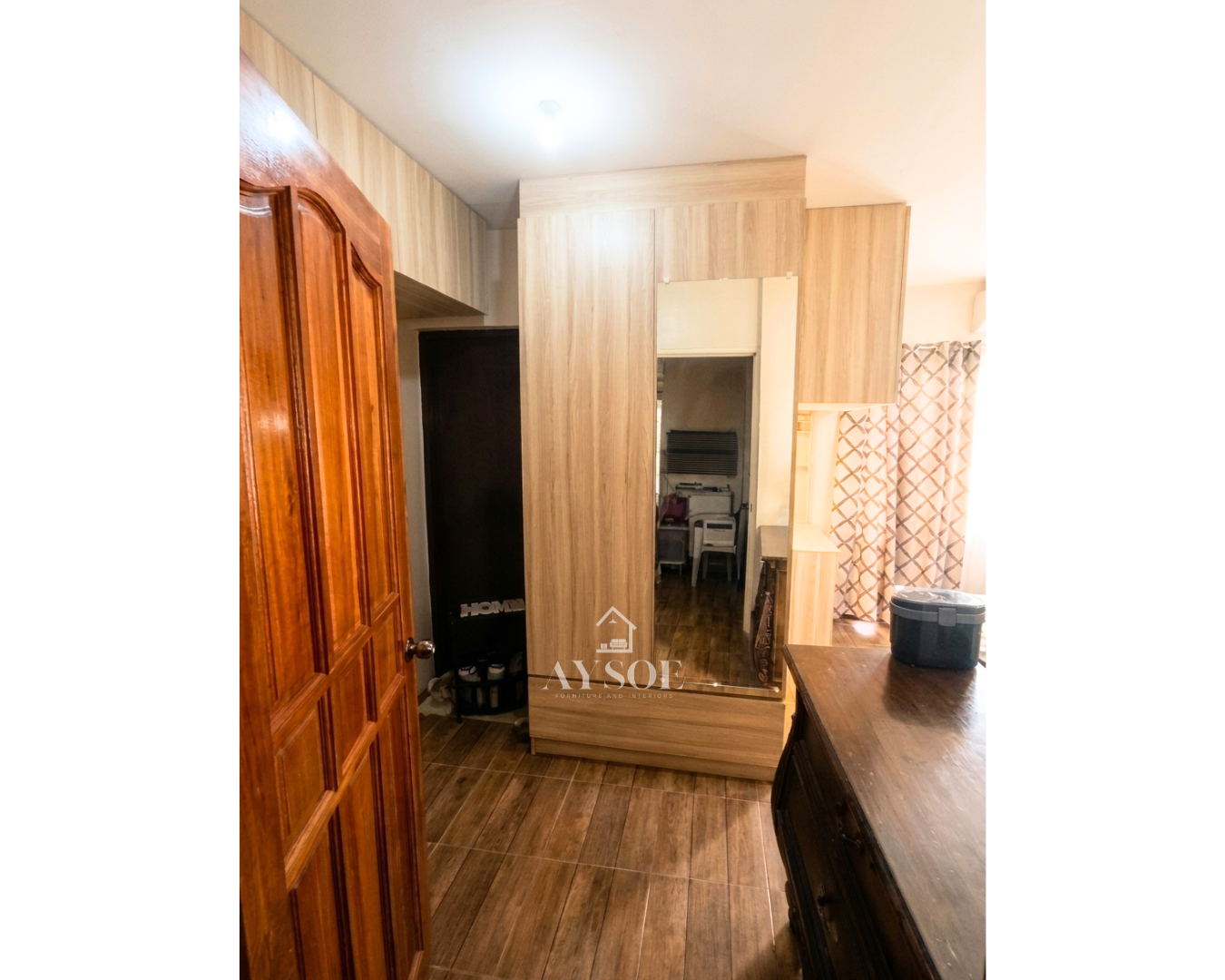 A custom light oak wardrobe with a full-length mirror door, a roomy bottom drawer, and overhead cabinets. Complete bedroom storage in a clean, modern design.