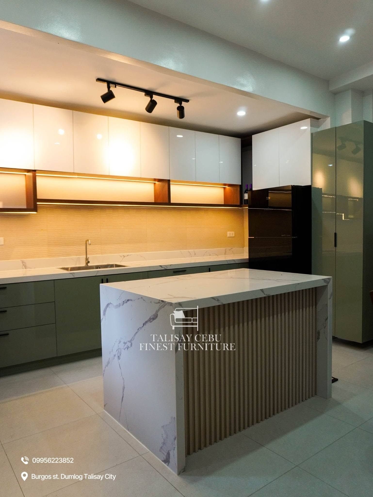 Upper Cabinet a row of handleless, glossy white overhead cabinets spans the wall. Below them is an open wooden shelving unit equipped with integrated warm LED strip lighting that illuminates the countertop.