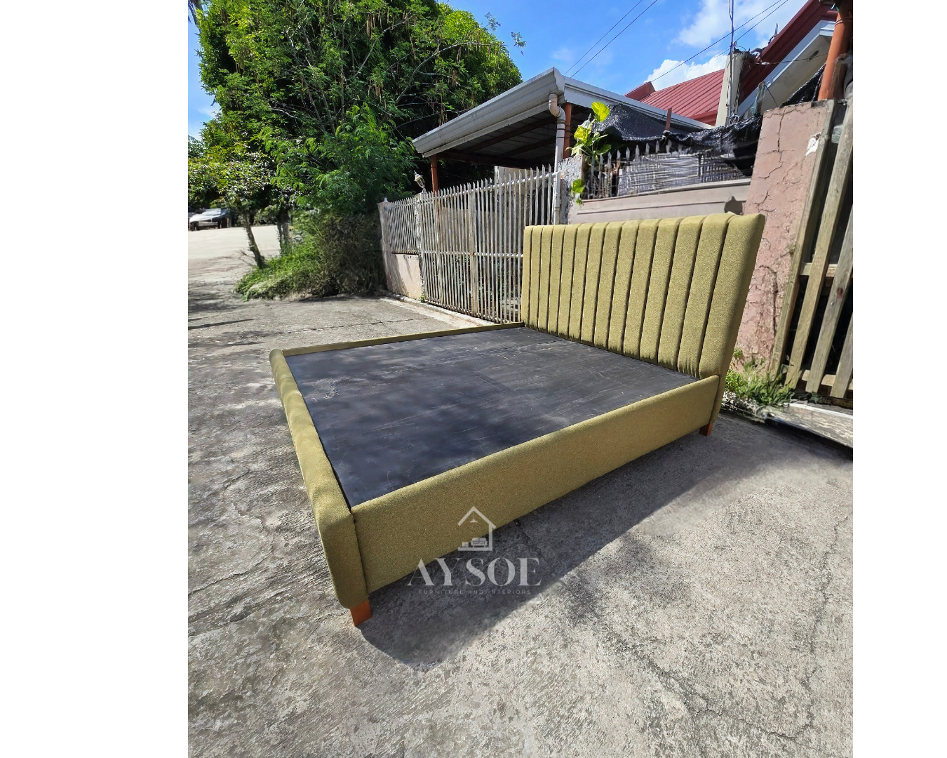 A modern platform bed frame upholstered in textured olive-green fabric, with a tall channel-tufted headboard and padded side rails. Stylish, sturdy, and easy to keep clean.