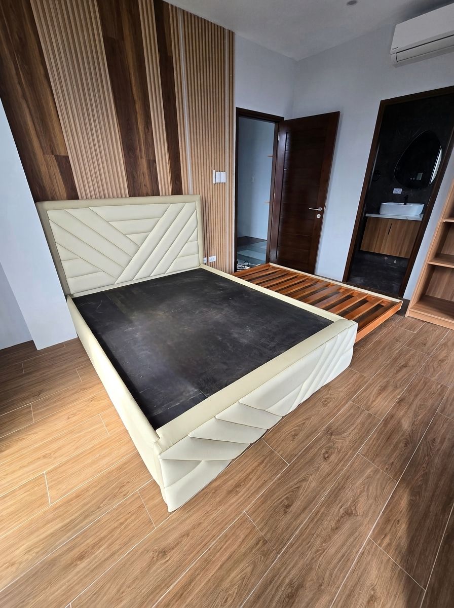 A modern upholstered bed in soft cream leatherette, with a geometric chevron headboard and matching footboard. A hidden pull-out trundle gives you a second sleeping space without taking up extra room.