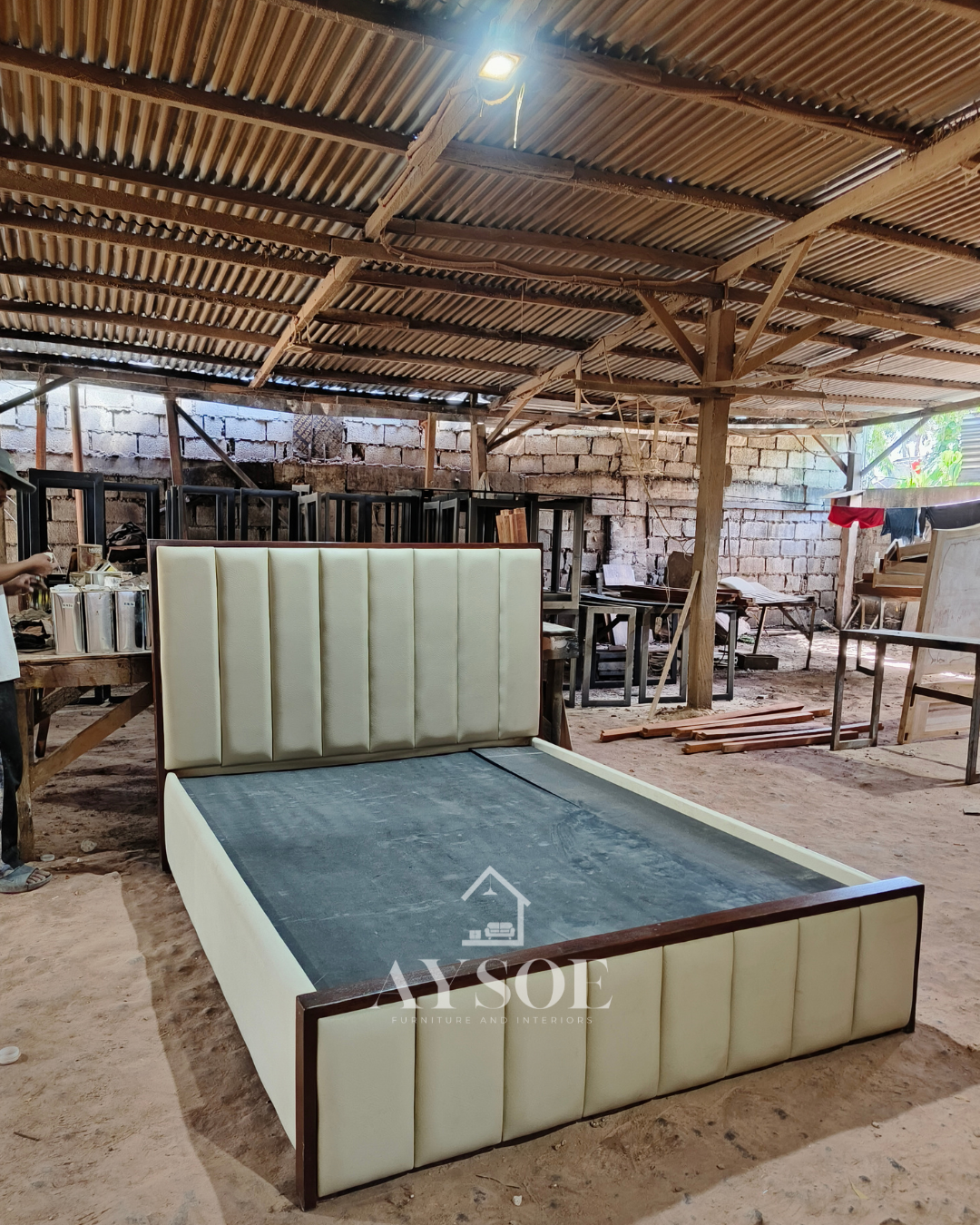 A platform bed frame in cream leatherette, with a tall channel-tufted headboard, a matching footboard, and dark mahogany wood trim. Clean, elegant, and built to last.
