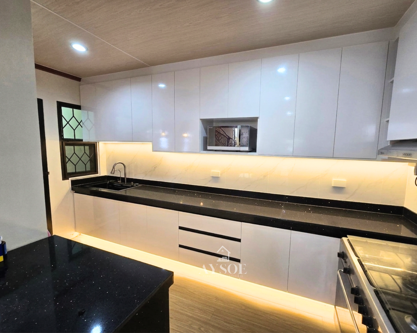 Glossy white kitchen cabinets with a wood bar counter and island. Spacious and stylish.