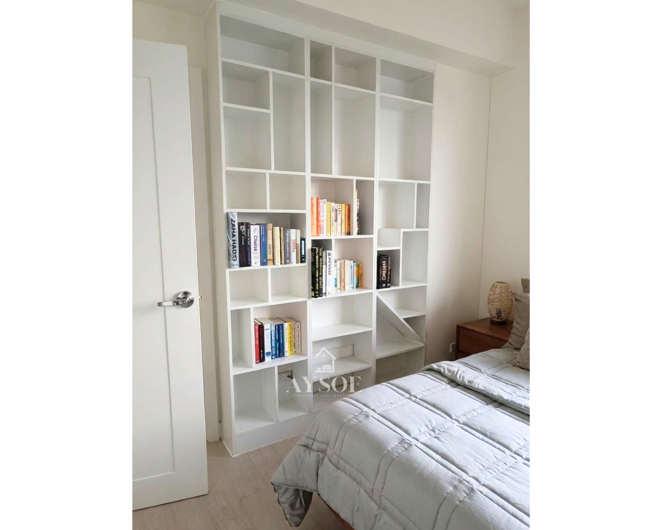 A floor-to-ceiling white bookshelf with geometric open cubbies in mixed sizes. Modern storage and display for books, decor, and collectibles.