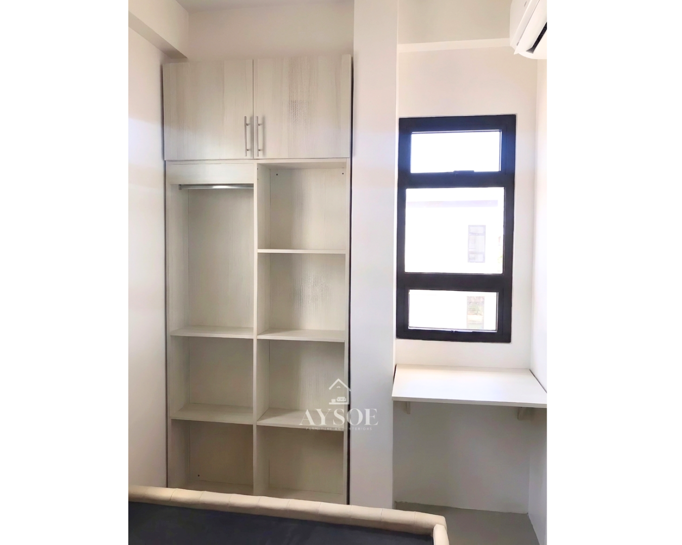 A custom space-saving wardrobe in a light oak wood-grain finish, with a hanging rod, open shelves, an overhead cabinet, and a floating desk. Smart storage for small bedrooms.