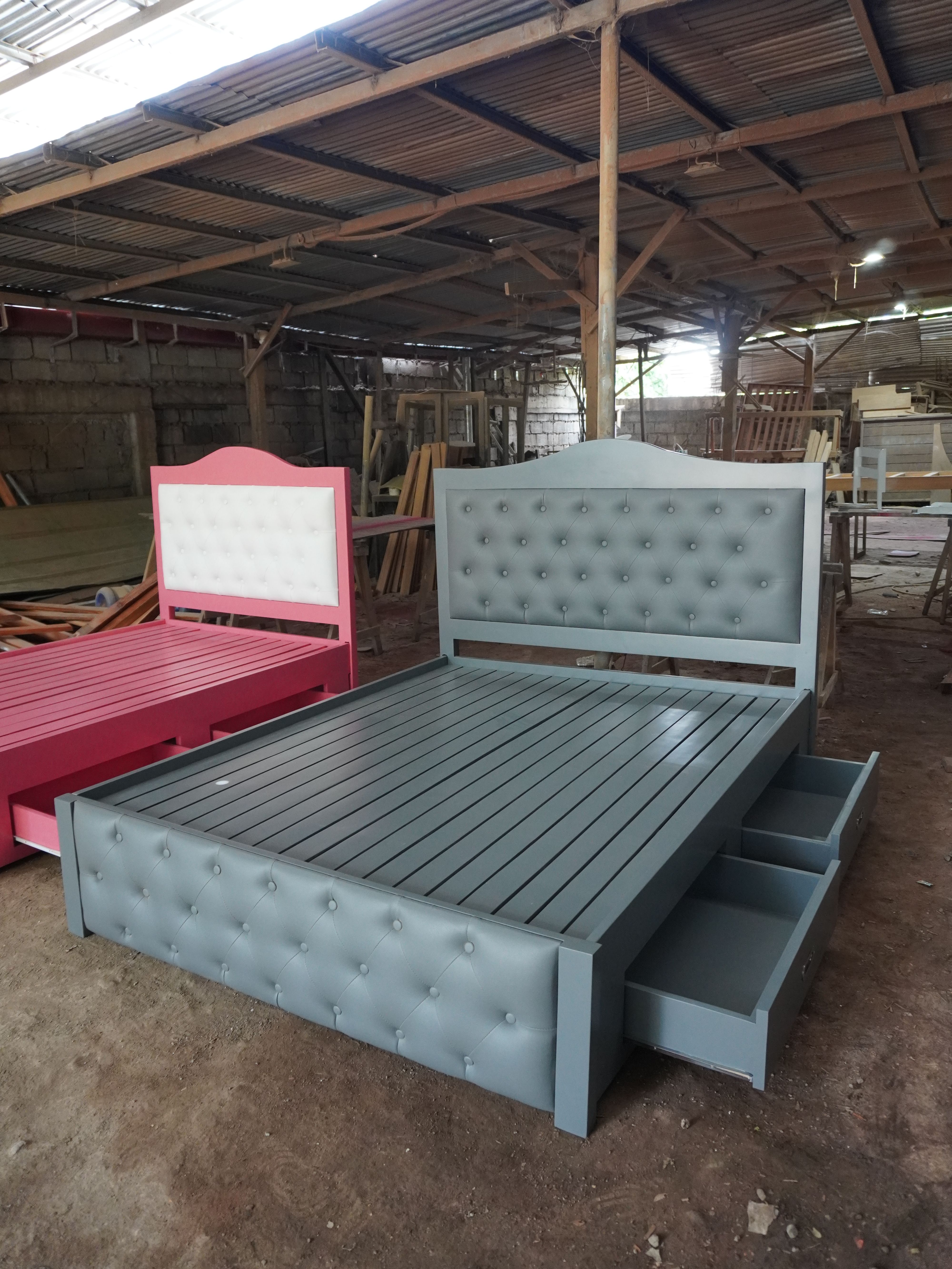 A classic storage bed in soft slate gray, with an arched wood-framed headboard, button-tufted leatherette panels on the headboard and footboard, and built-in side drawers with recessed metal pulls.