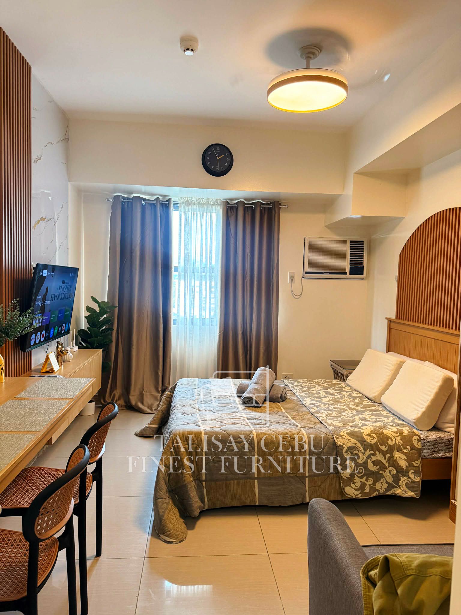 A warm, move-in-ready studio with wood-slat accent walls, a marble-look feature wall, built-in desk and TV console, and a cozy bed nook, fully finished and furnished.