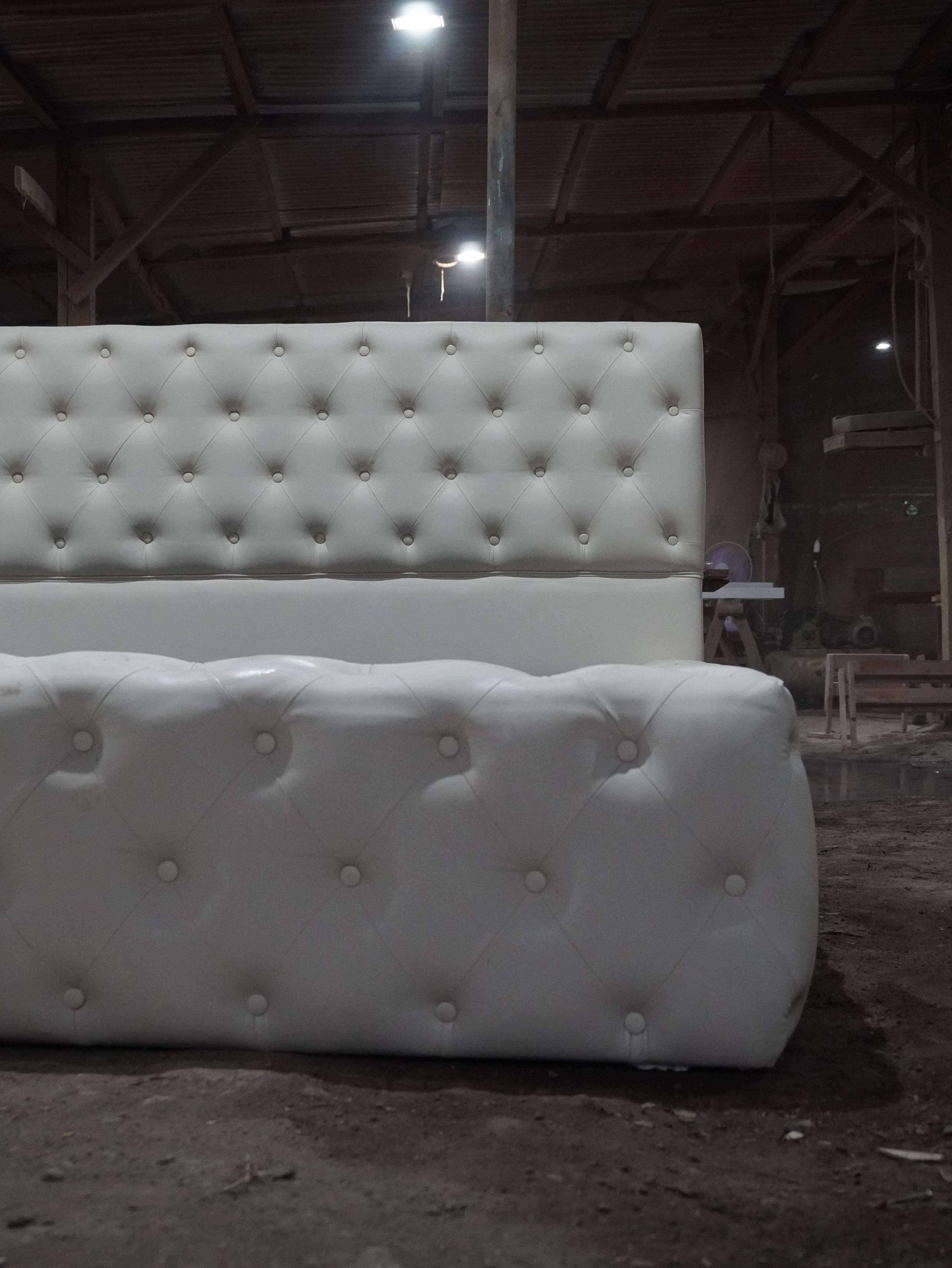 Sleep in luxury on this white button-tufted bed, with a tall padded headboard and a plush, wraparound footboard for a statement bedroom look