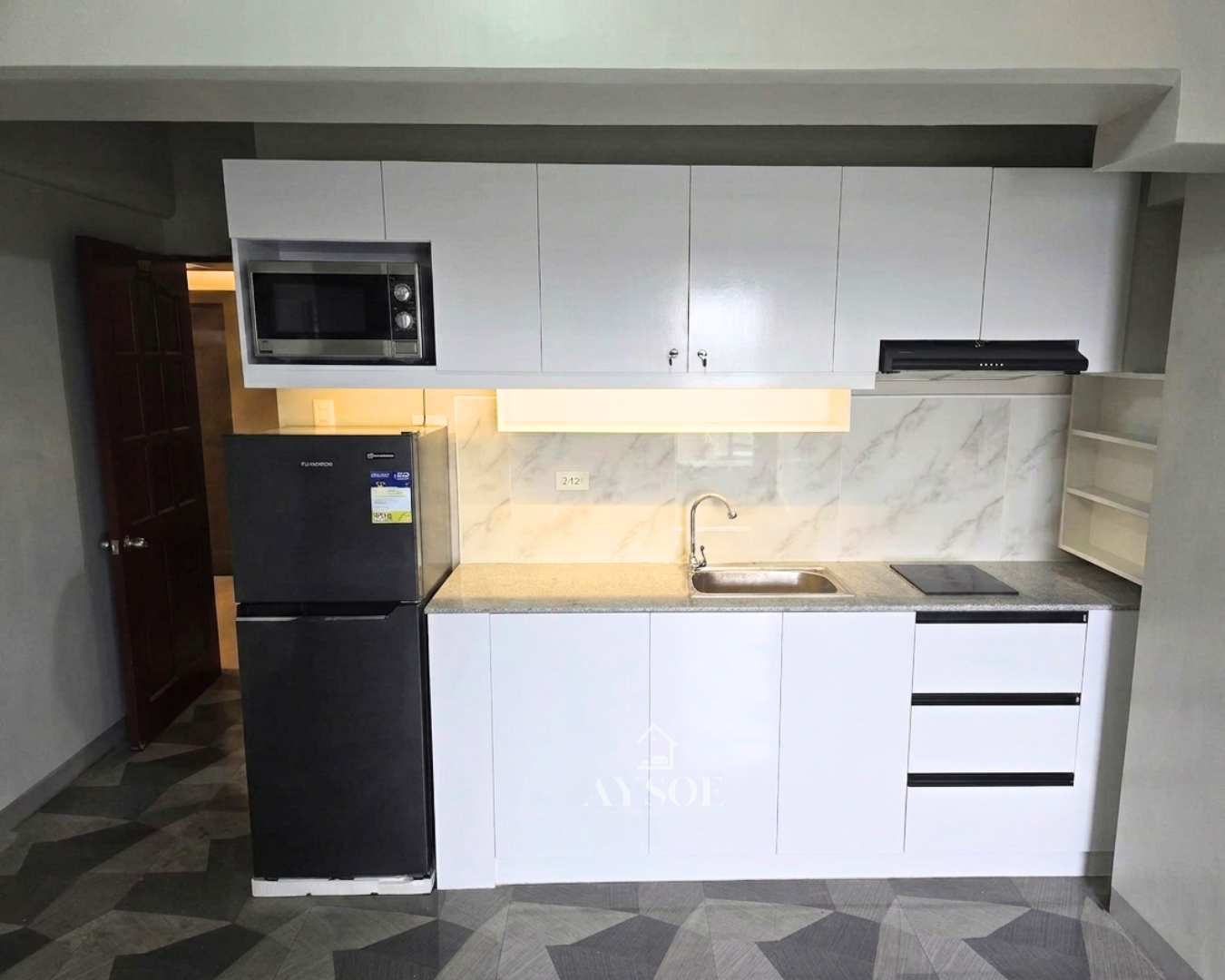 A compact straight kitchen set with glossy white cabinets, a built-in microwave niche, three drawers, and a granite-look countertop. Clean, bright, and made for condos and studios.