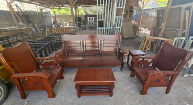 A matching rectangular wooden center table with a two-tiered design (including a lower storage shelf) sits in the middle. Two matching square wooden side tables are placed in the corners between the seating.