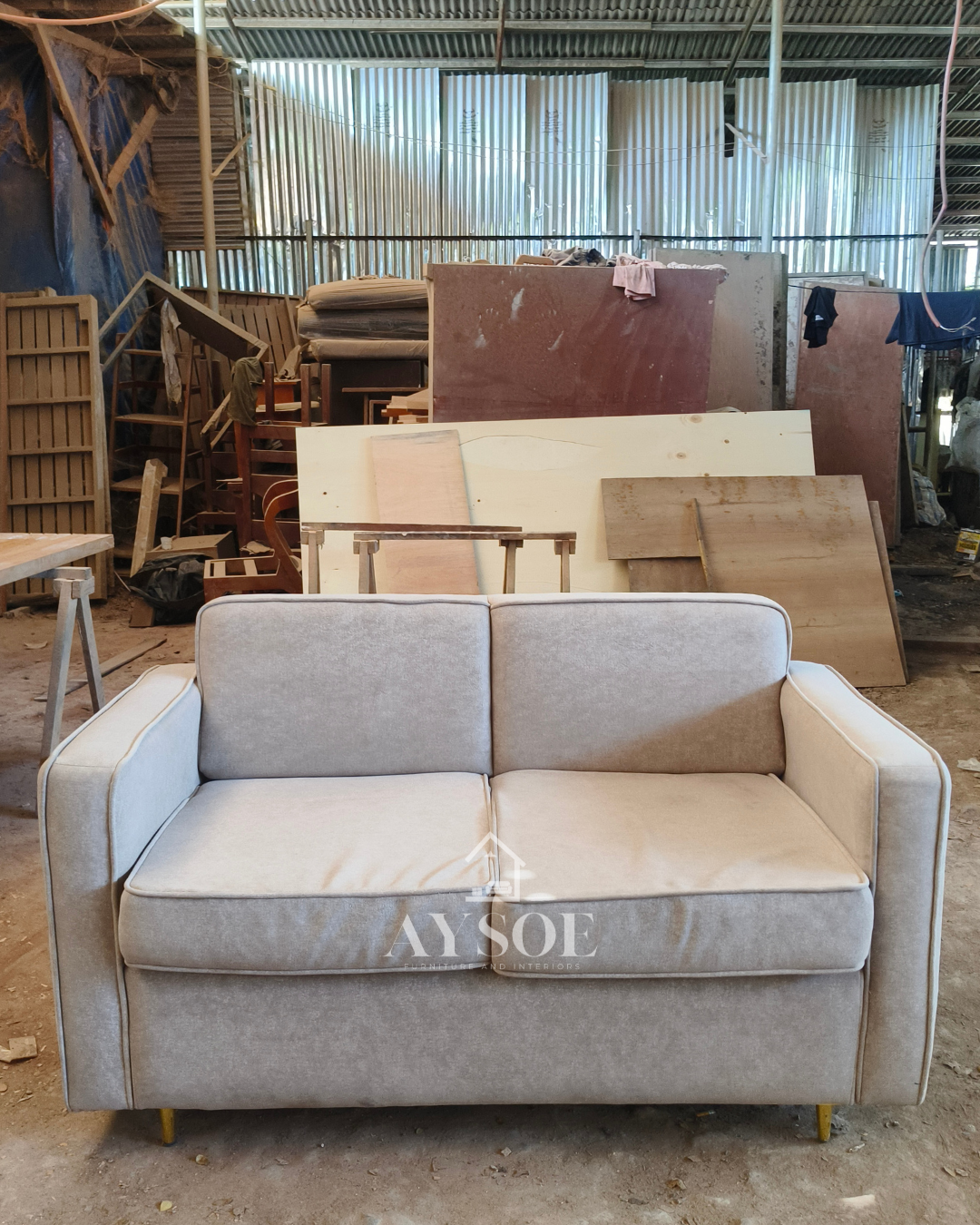 A modern 2-piece living set in soft light grey fabric: a two-seater loveseat and a matching armchair with thick cushions and slim gold legs. Compact, comfortable, and stylish.