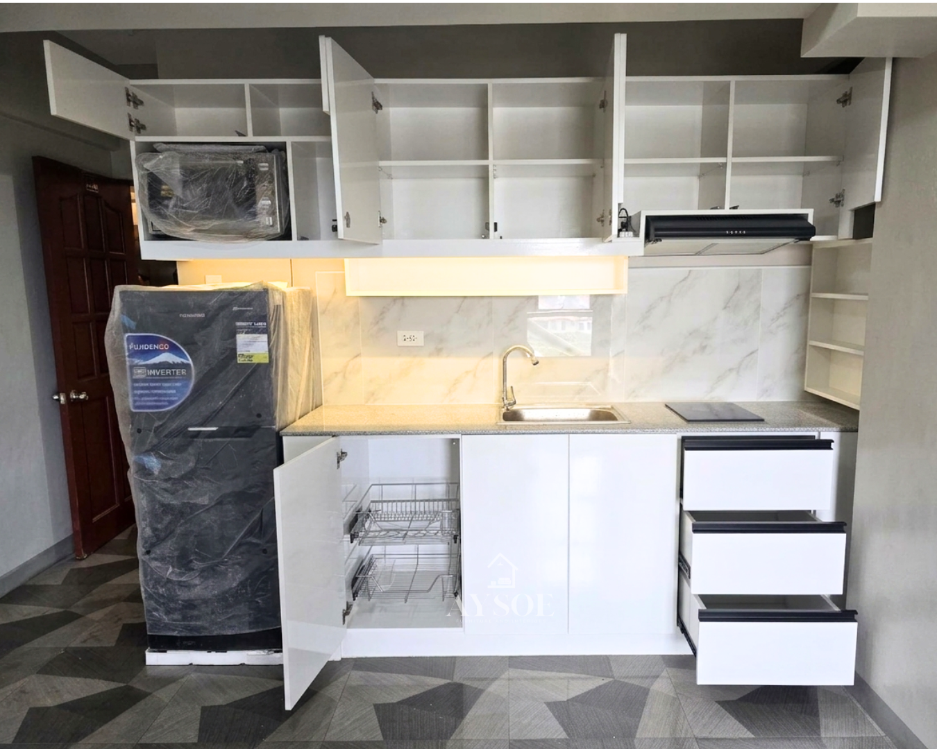 A compact straight kitchen set with glossy white cabinets, a built-in microwave niche, three drawers, and a granite-look countertop. Clean, bright, and made for condos and studios.