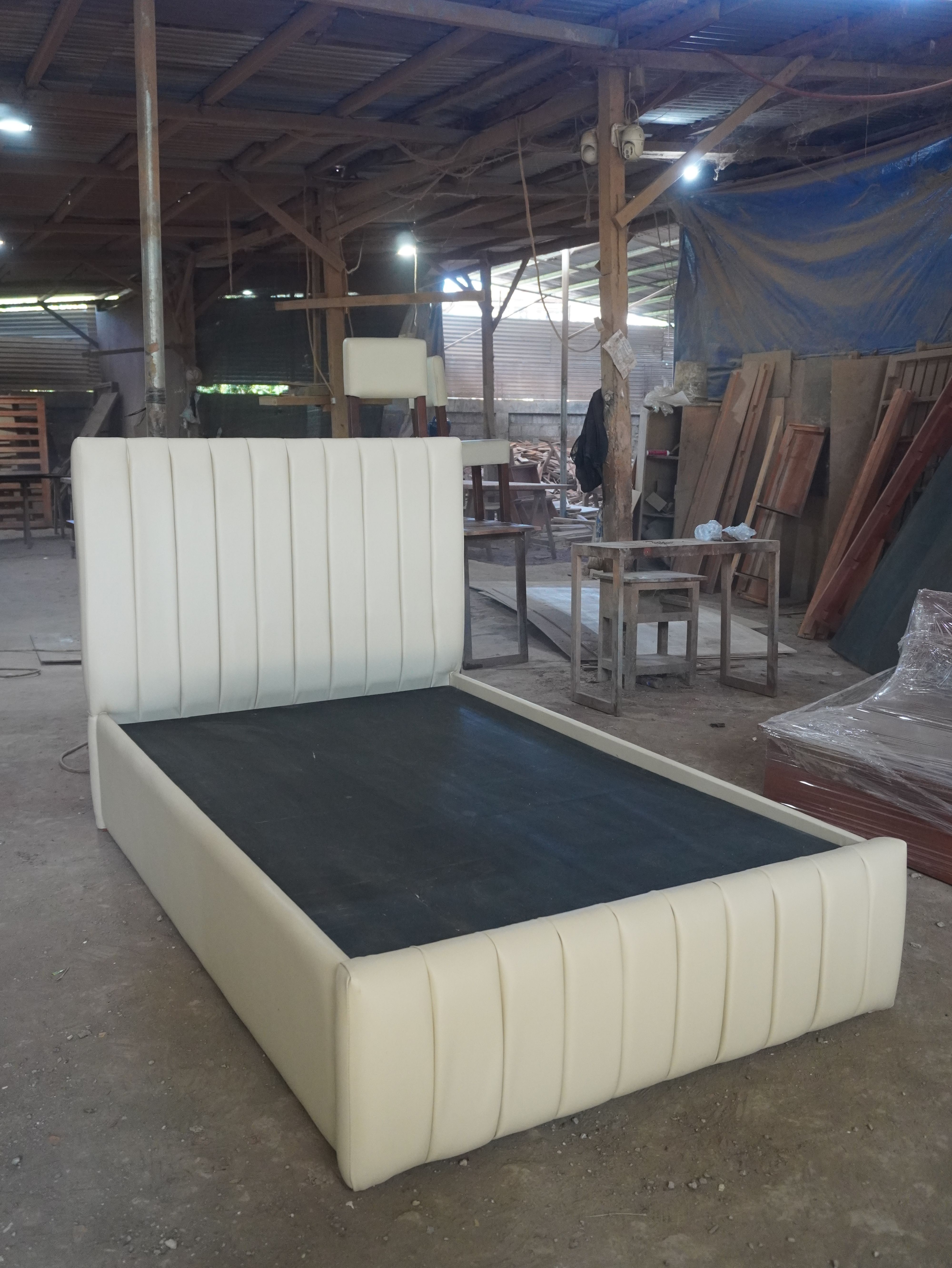 A clean, modern upholstered bed in soft cream leatherette, with vertical channel panels on the headboard and footboard. Fully wrapped frame, easy-to-wipe finish, and a solid platform base.
