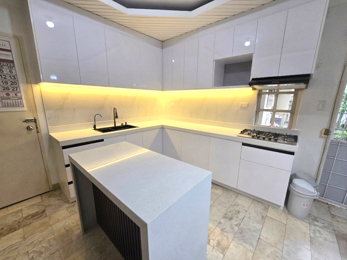 A high-gloss white L-shaped kitchen with a marble-look backsplash, LED lighting, and a waterfall island.