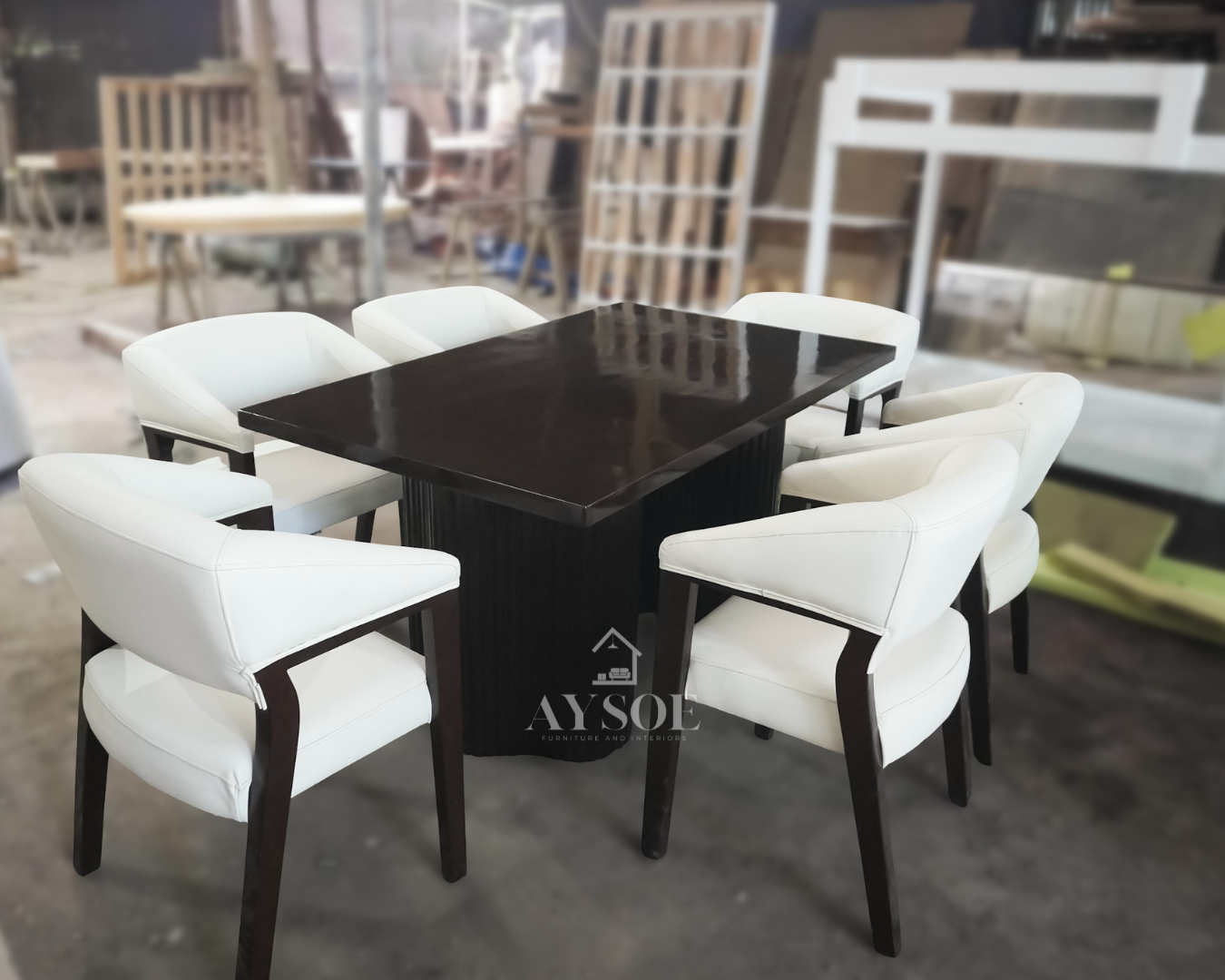 A modern 6-seater dining set with a glossy dark tabletop on a fluted pedestal base and six white leatherette armchairs with wraparound backs. Elegant, wipe-clean, made to order.