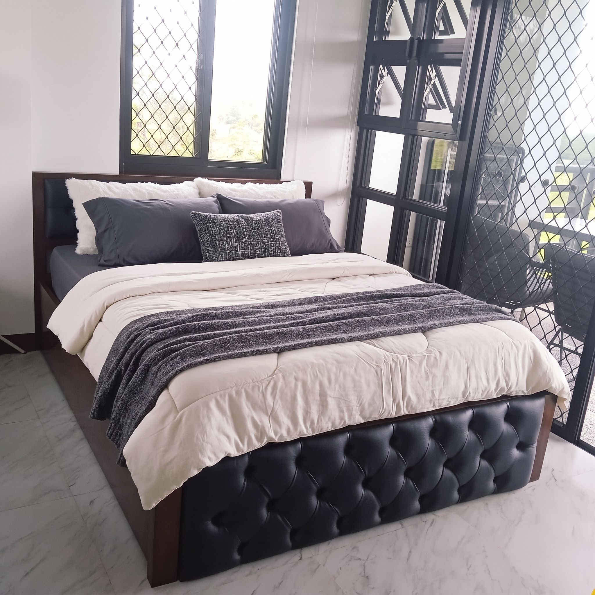 A solid wood bed in a rich, glossy dark walnut finish, with a black button-tufted leatherette headboard panel, a matching tufted footboard, and a sturdy slatted base. Bold, classic, and built to last.