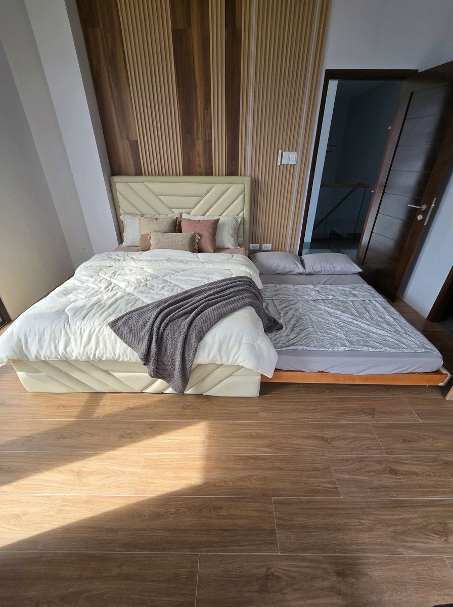 A modern upholstered bed in soft cream leatherette, with a geometric chevron headboard and matching footboard. A hidden pull-out trundle gives you a second sleeping space without taking up extra room.