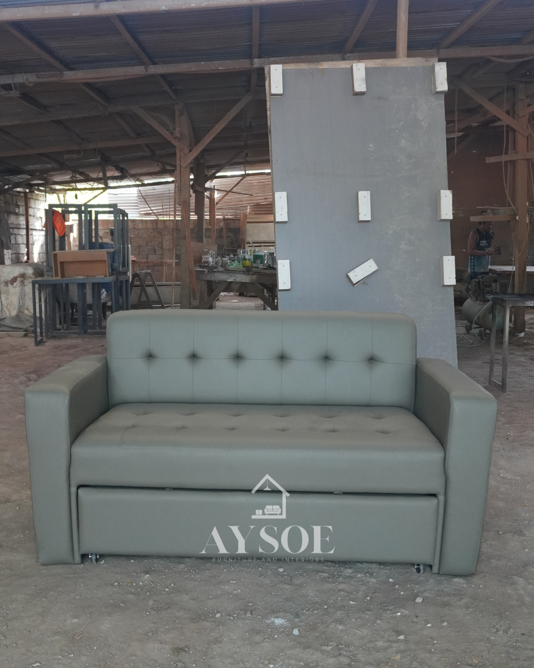 A 2-seater sofa that pulls out into a bed, in sage grey-green leatherette with a button-tufted back and seat. Two pieces of furniture in one, great for small spaces and guests.