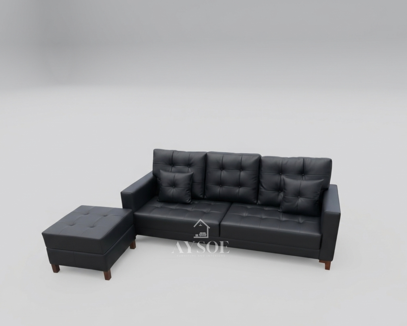 A modern black leatherette three-seater sofa with square-tufted cushions, boxy arms, two throw pillows, and a matching ottoman on slim wood legs. Sleek, easy to wipe clean, and made to order.