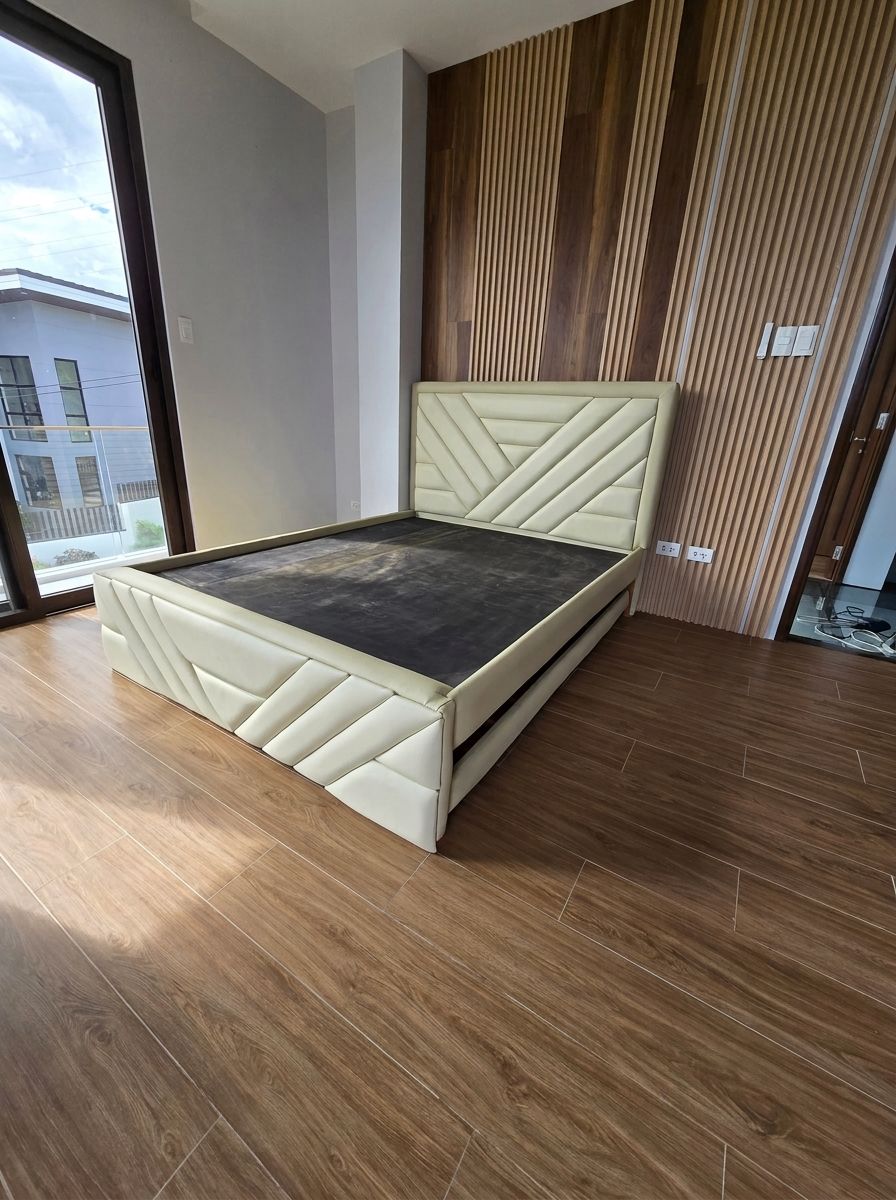A modern upholstered bed in soft cream leatherette, with a geometric chevron headboard and matching footboard. A hidden pull-out trundle gives you a second sleeping space without taking up extra room.