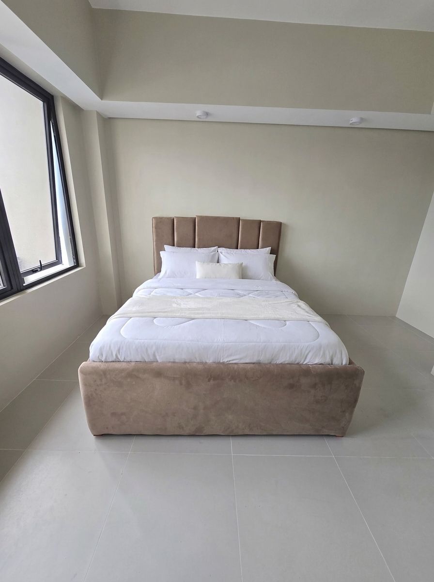 A modern upholstered bed in soft taupe suede-style fabric, with a vertical channel headboard and a gas-lift base that opens to a huge hidden storage space. Clean, calm, and built to save space in condos and bedrooms.