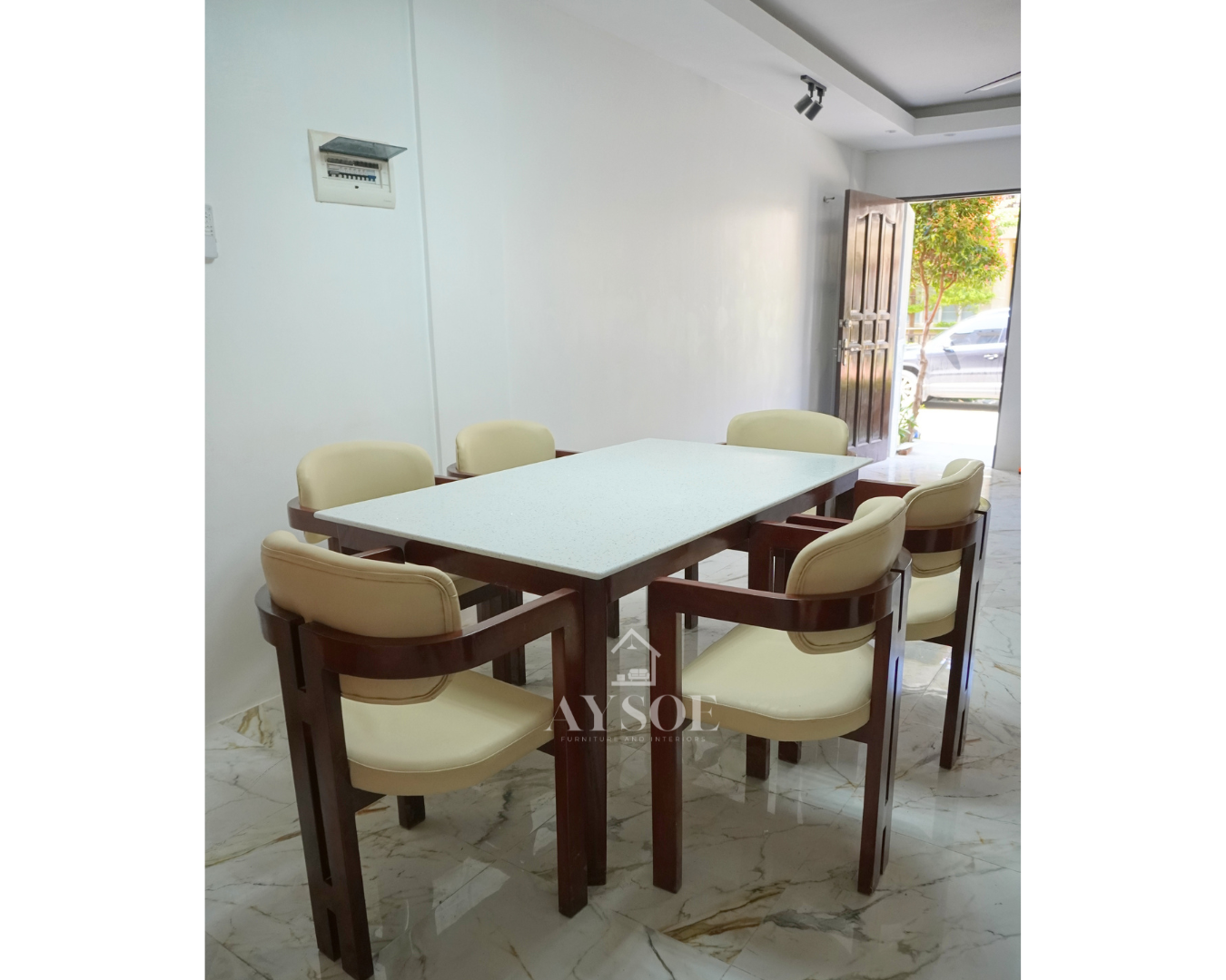 A 6-seater dining set with a white speckled stone-look tabletop on a glossy mahogany wood base, plus six curved-back armchairs with cream leatherette cushions. Elegant, wipe-clean, made to order.